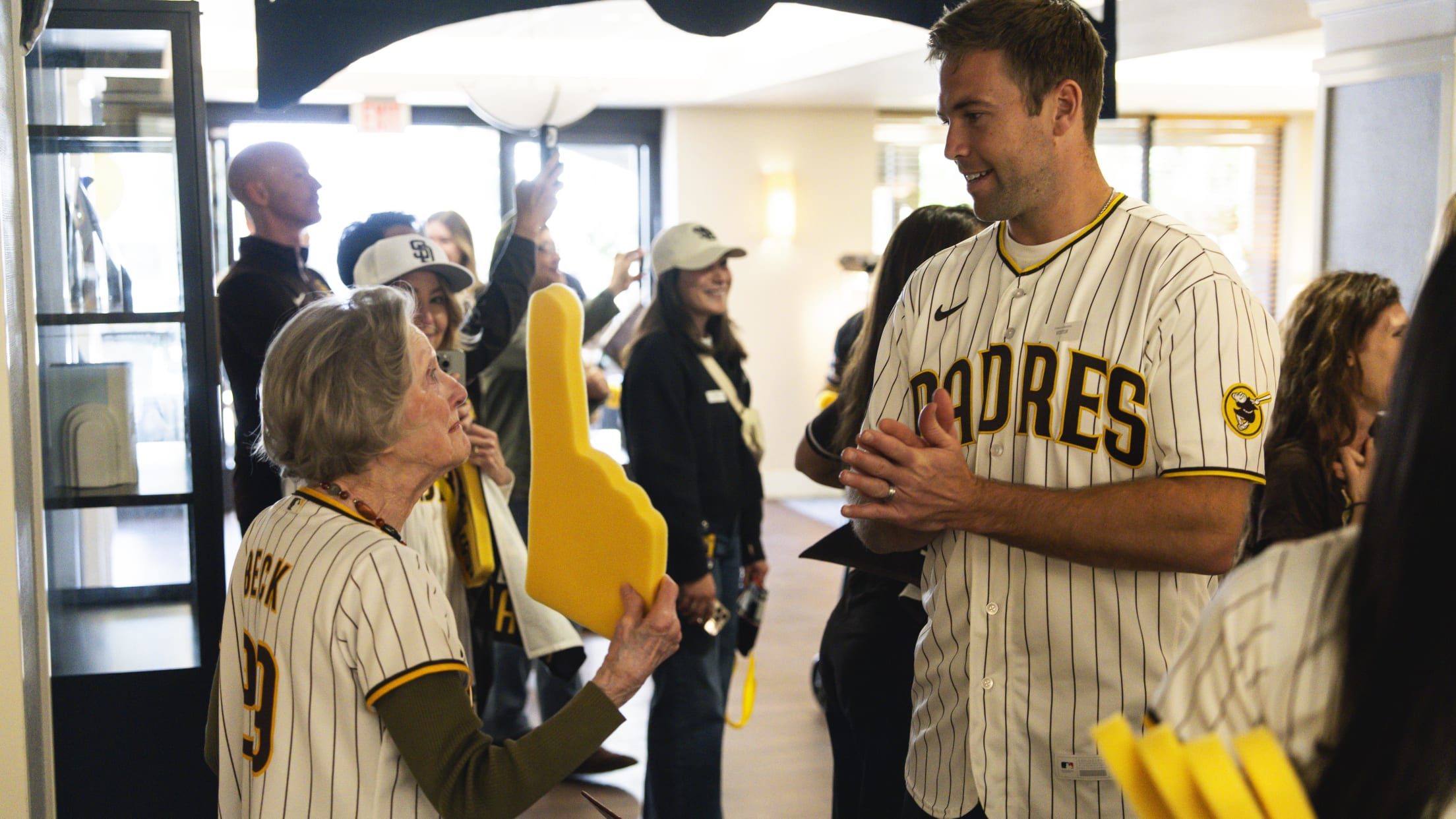 Jason Adam interacts with a San Diego Padres fan holding a foam finger.