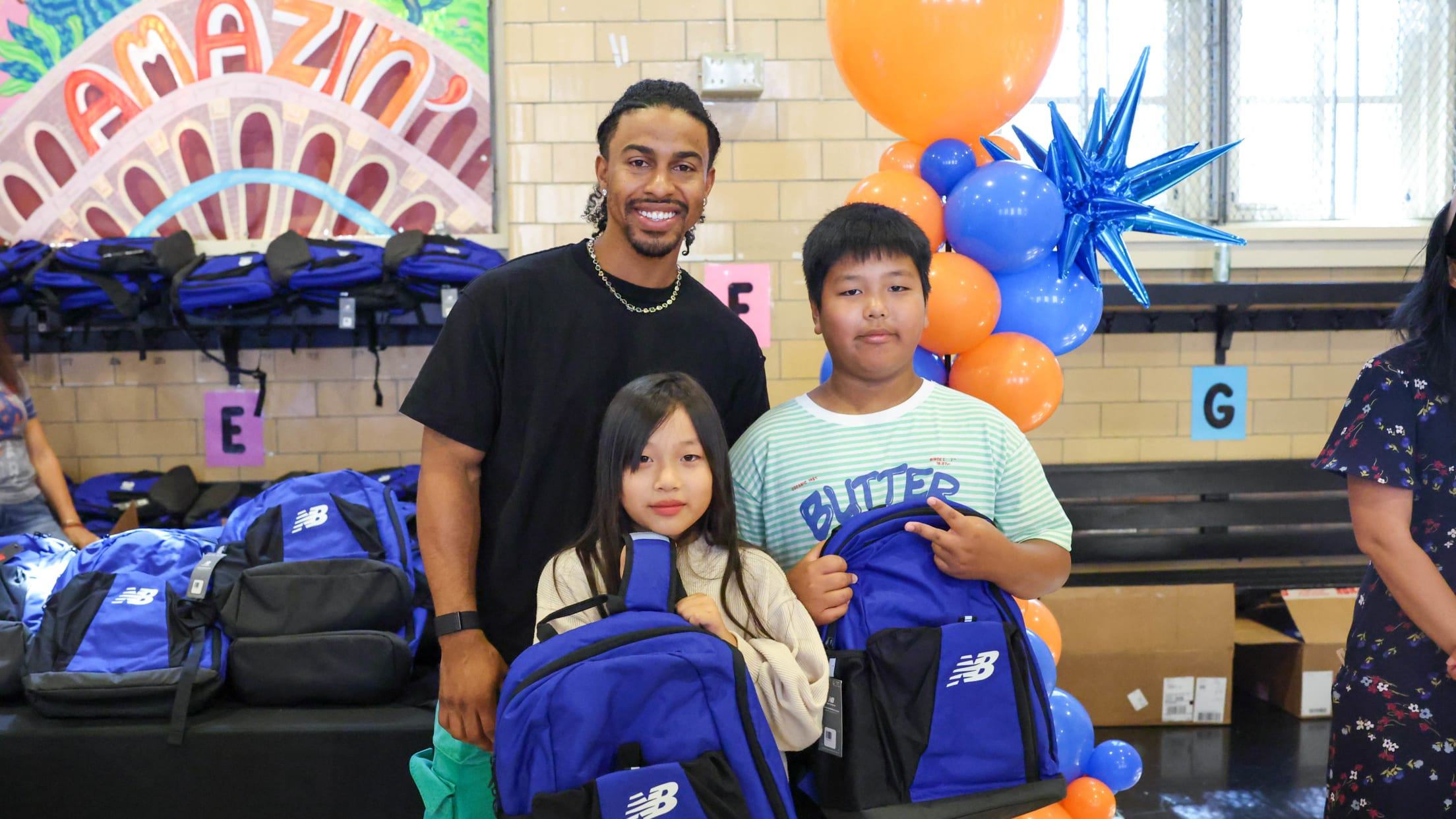 Francisco Lindor takes a photo with students receiving New Balance backpacks.