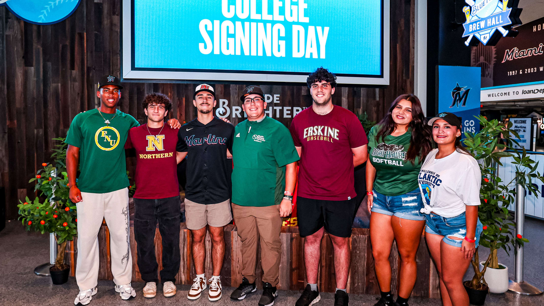 Miami Marlins Youth Academy athletes stand at College Signing Day with their college apparel.