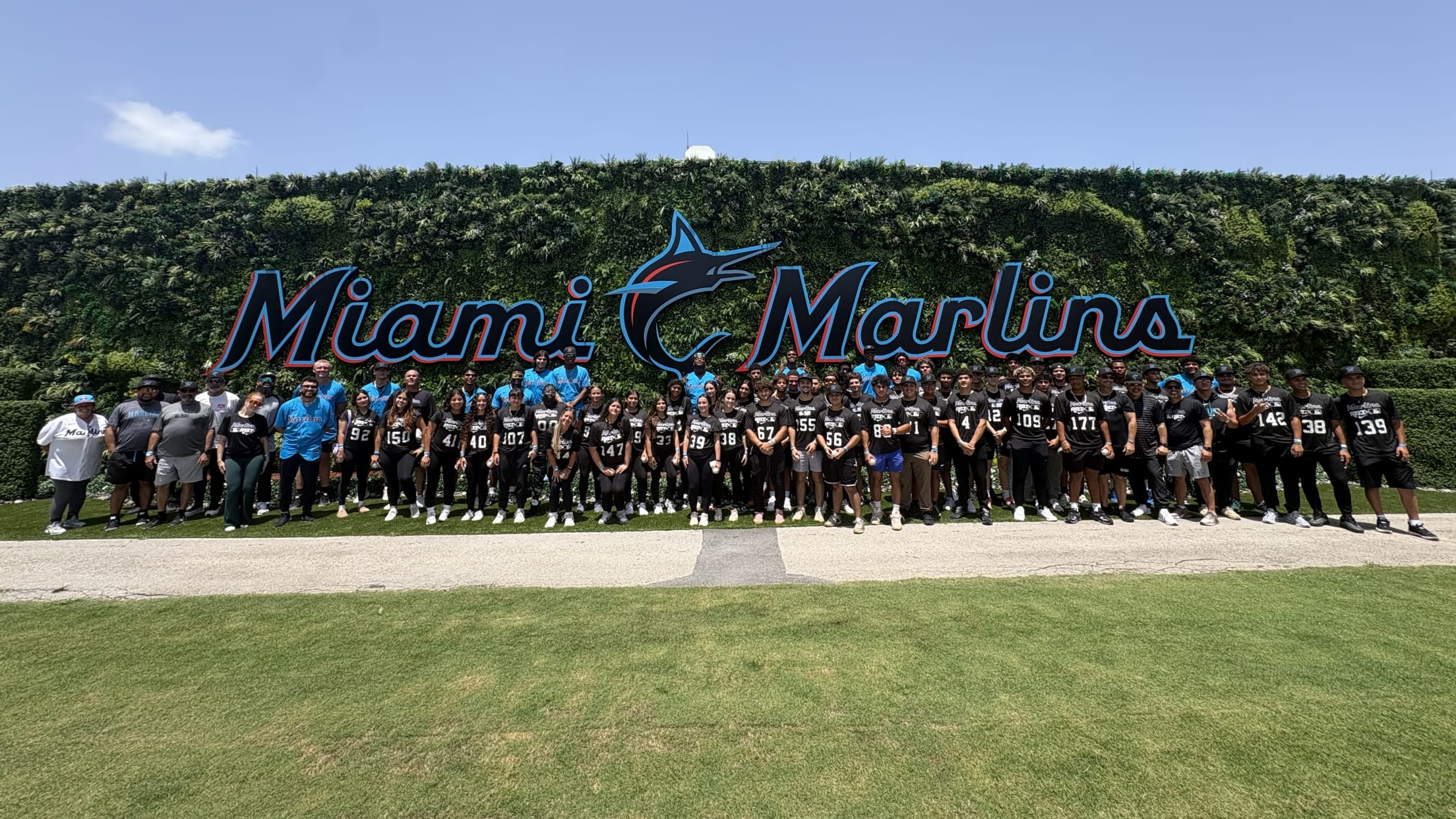 Coaches and players from the Marlins Nike RBI All-Stars Southeast Region pose for a group photo in front of a large Miami Marlins sign.
