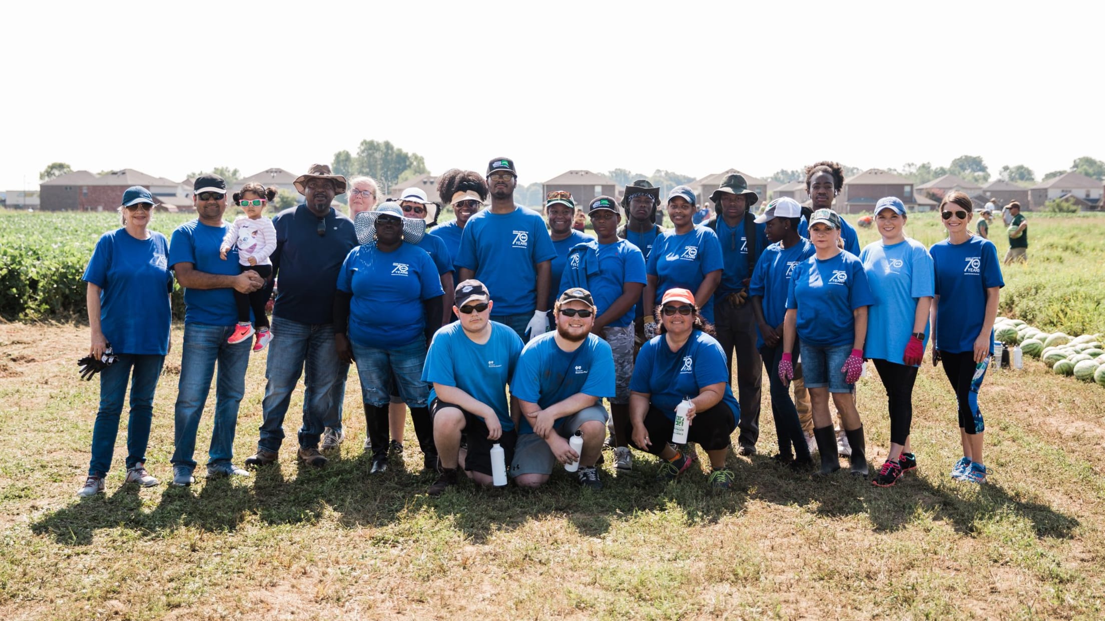 Volunteers take a group photo in a farm field.