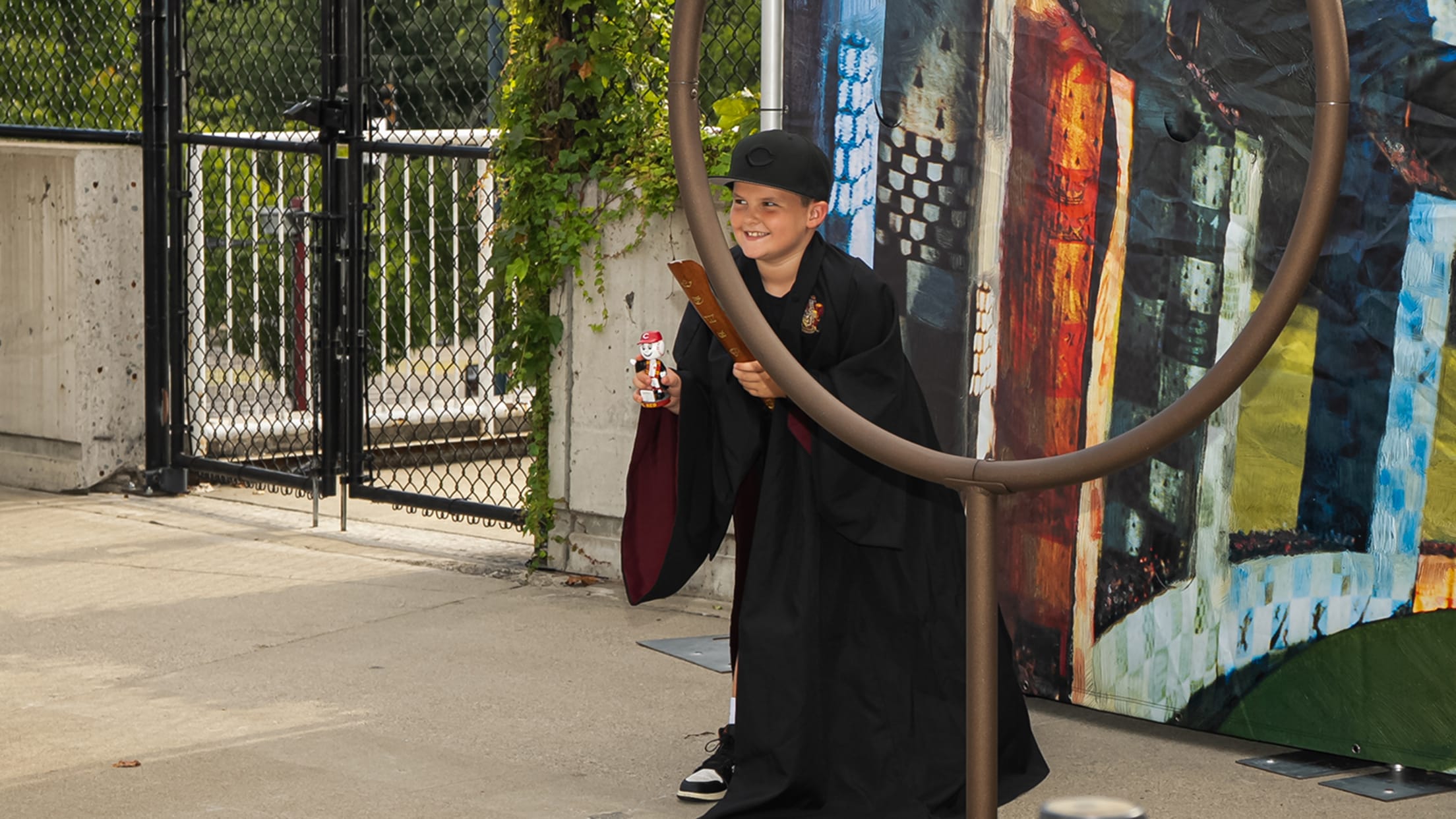 Young fan holding his Mr. Red Harry Potter™ bobblehead in front of Quidditch photo backdrop.