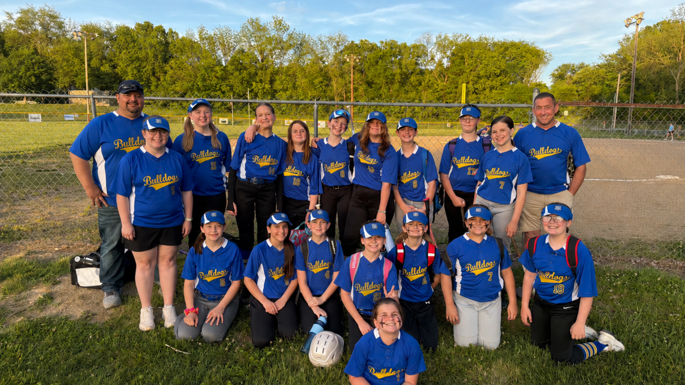 The Bulldogs take a team photo on the side of a dirt field.