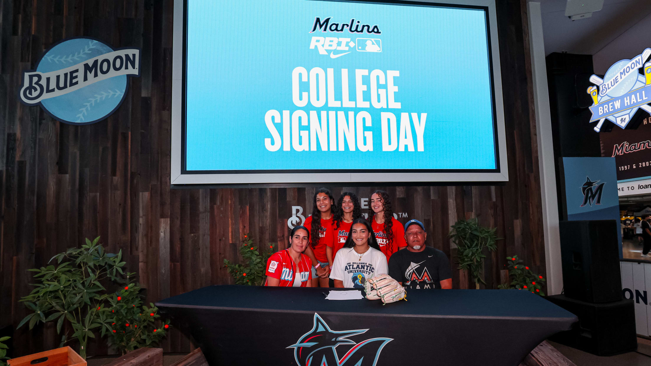 A player sits with her family and poses for a photo at the Marlins Nike RBI College Signing Day.