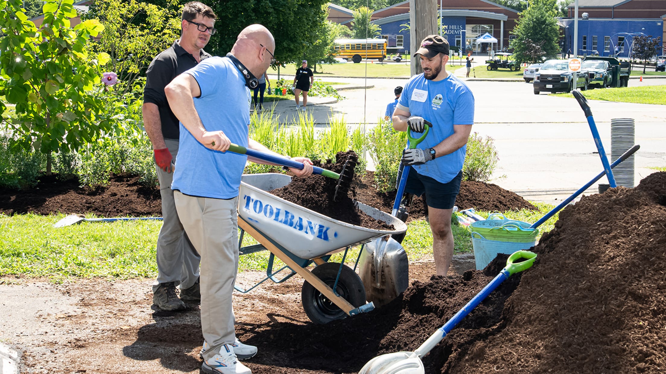 Volunteers moving dirt with a wheelbarrow.