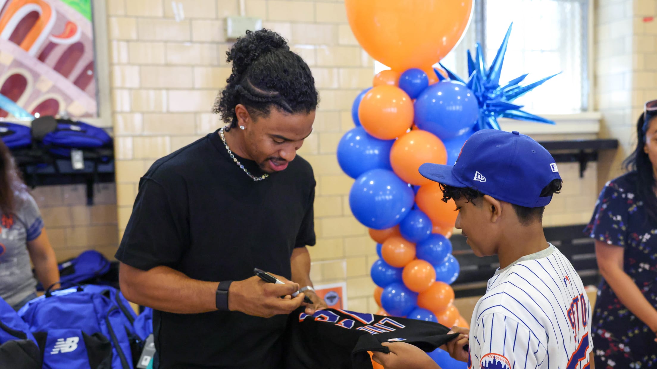 Francisco Lindor signs a shirt for a young New York Mets fan.