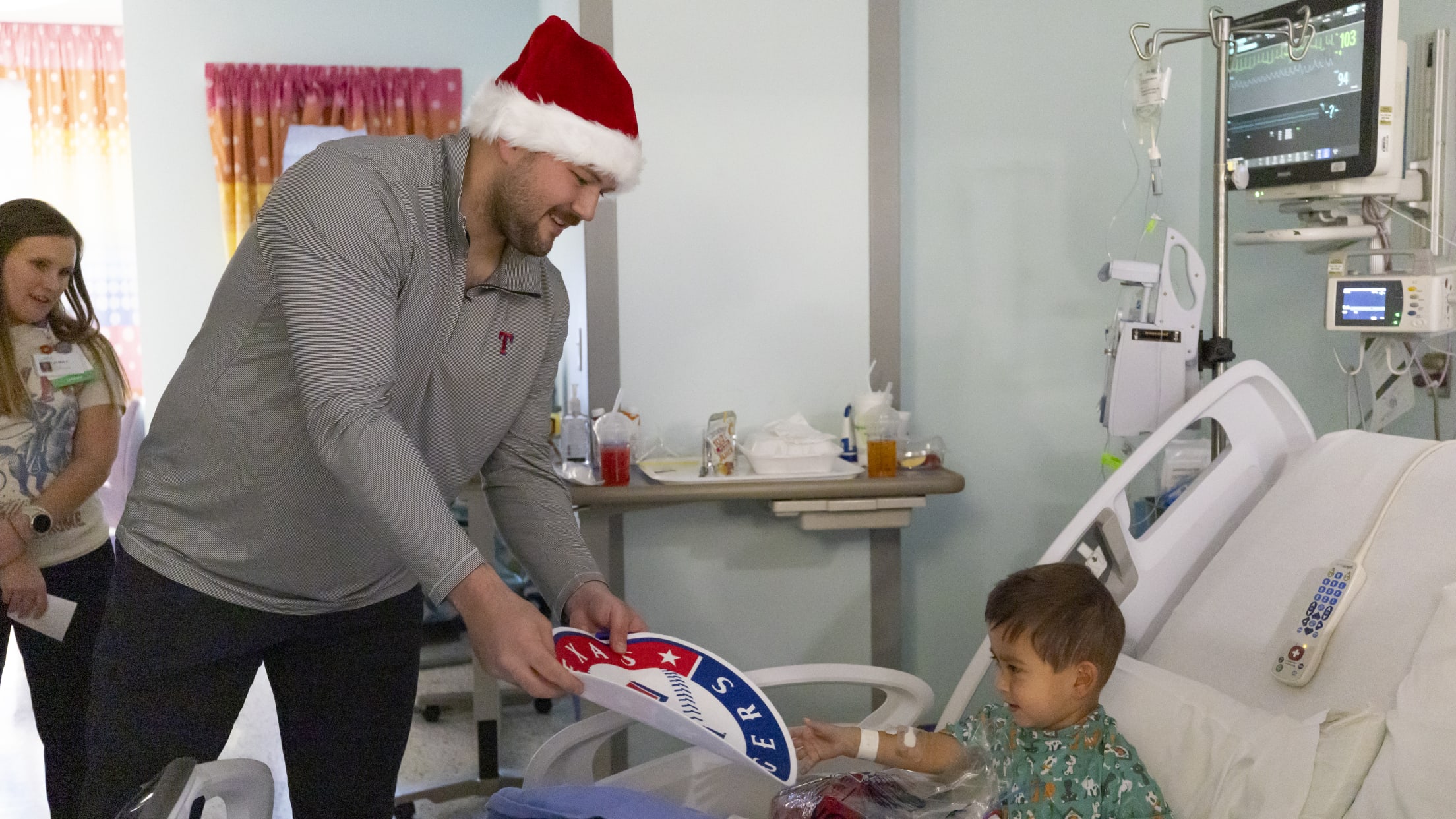 Jake Burger hands a young fan a Texas Rangers poster during a hospital visit.