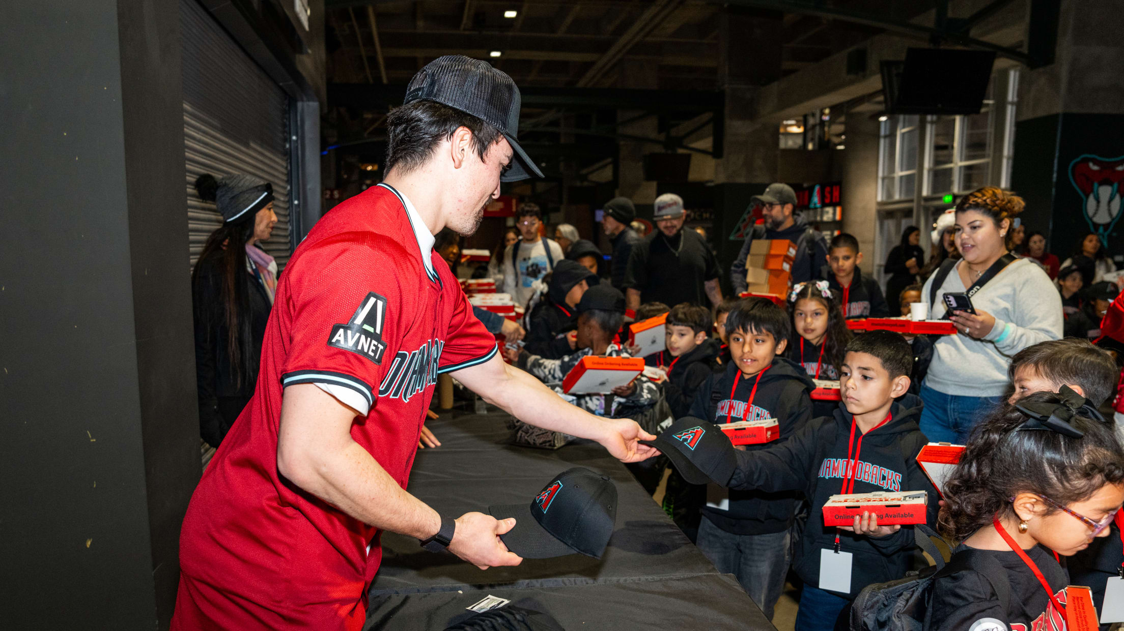 Corbin Carroll hands out Arizona Diamondbacks caps to young fans.