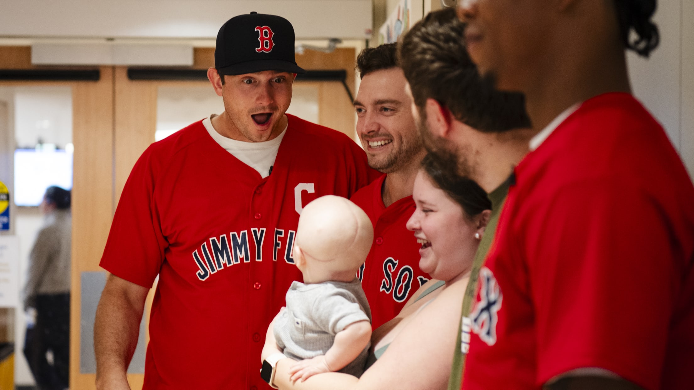 Garrett Whitlock plays with a baby as they pose for a photo.