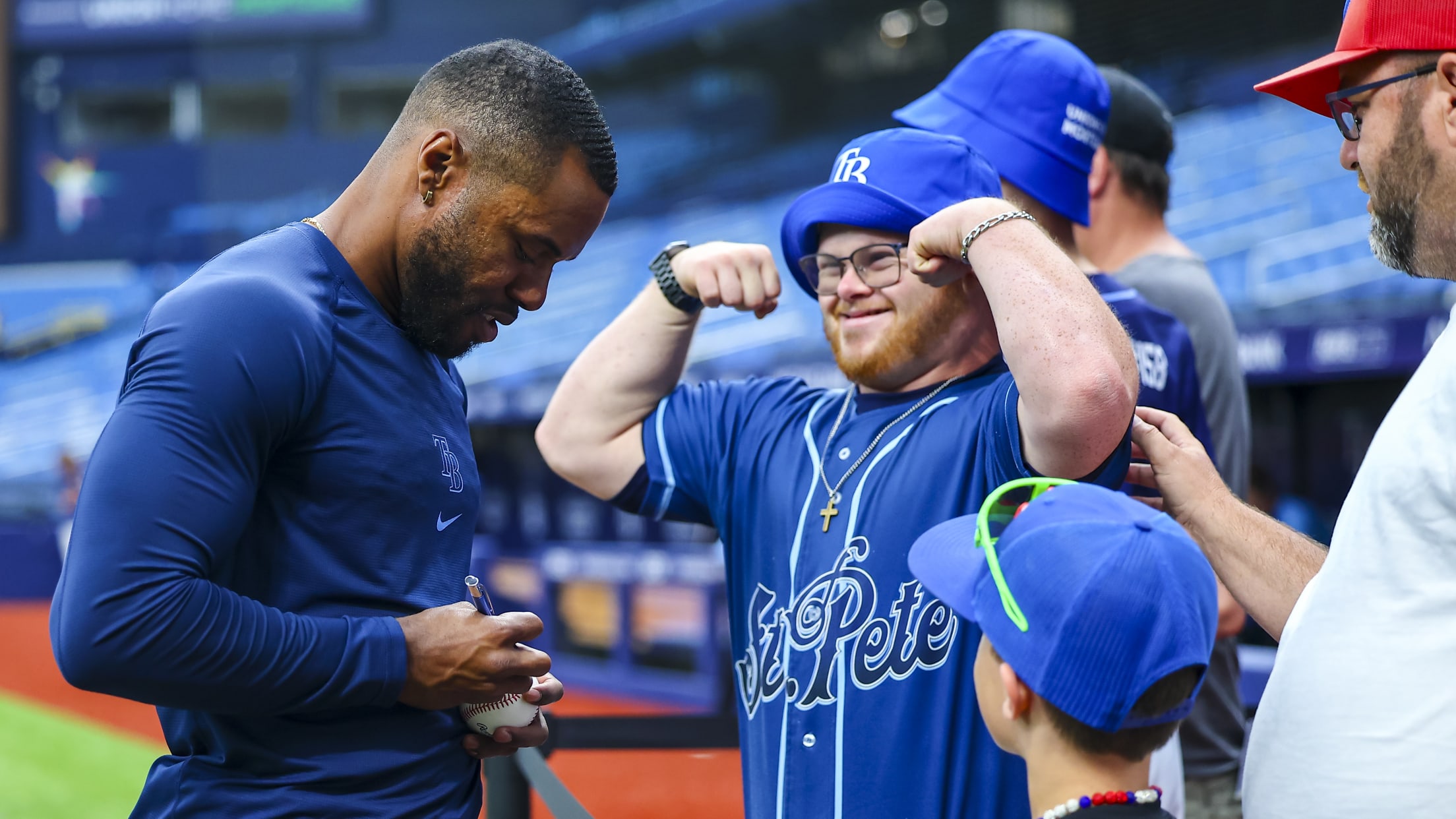 Cedric Mullins signs a baseball for a fan who is flexing his muscles.