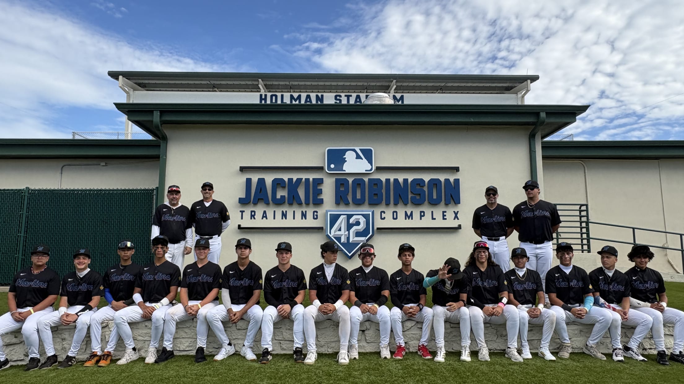 Coaches and players pose for a team photo outside Holman Stadium at the Jackie Robinson Training Complex.