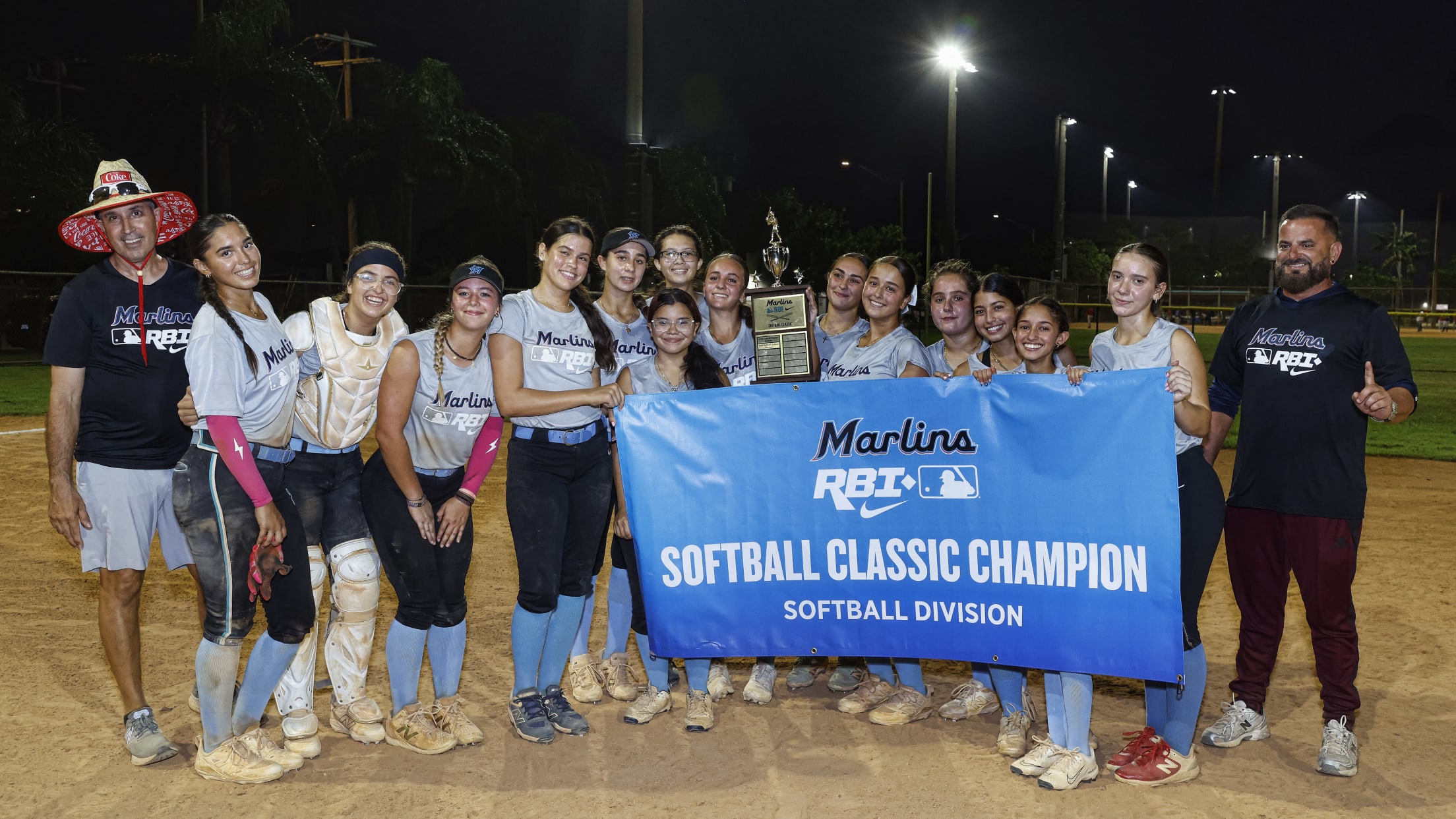The championship team poses for a group photo behind a Marlins Nike RBI Softball Classic Champion banner.