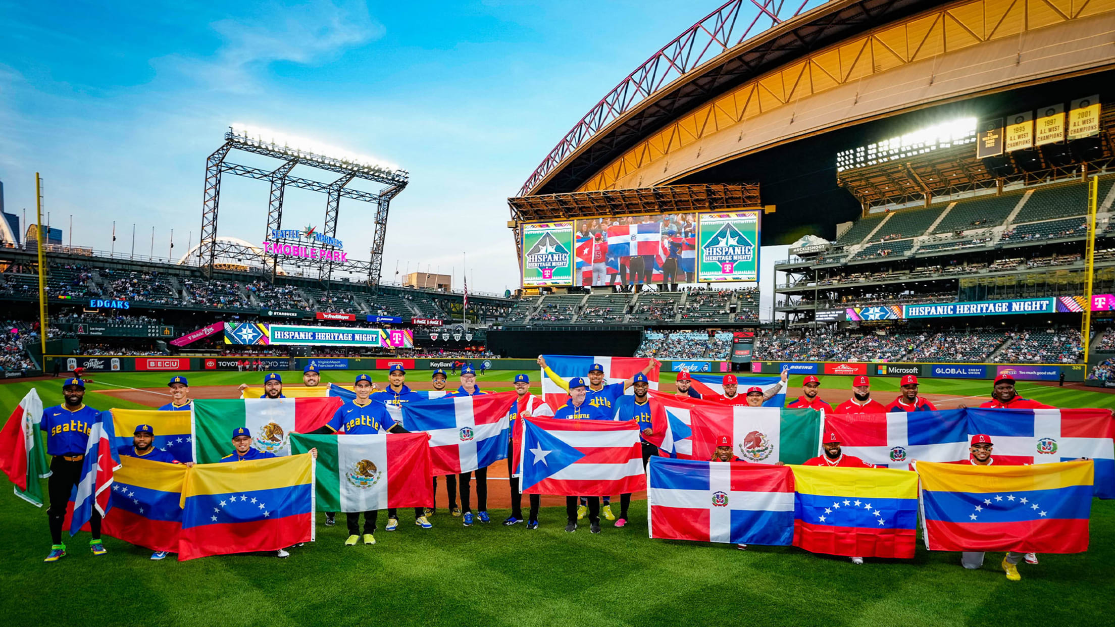 Image of Mariners players and Angels players holding up flags representing their home country during the Hispanic Heritage Night pregame ceremony.