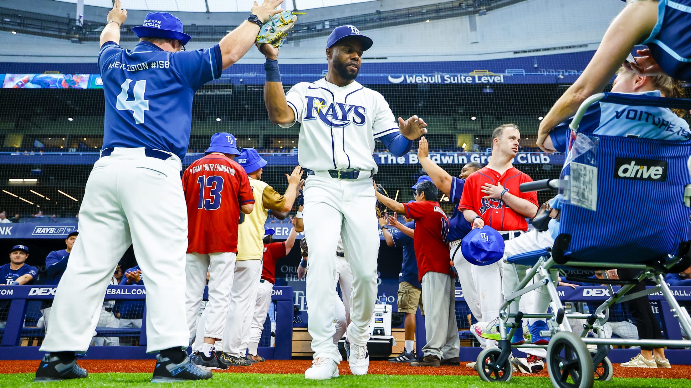 Cedric Mullins high fives fans as he step out the dugout at Tropicana Field.