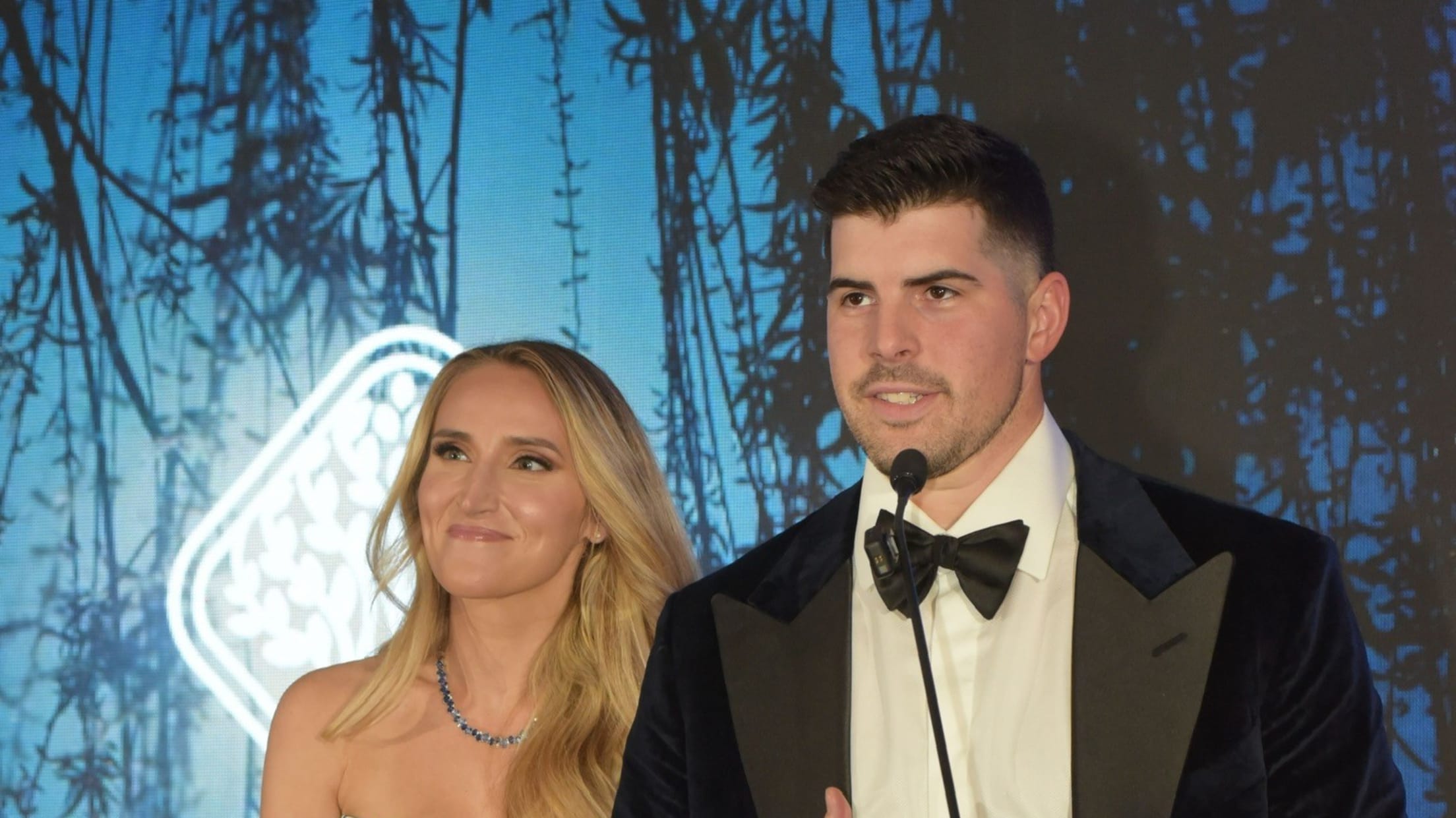 Carlos and Ashley Rodón stand behind a podium and speak at a gala.
