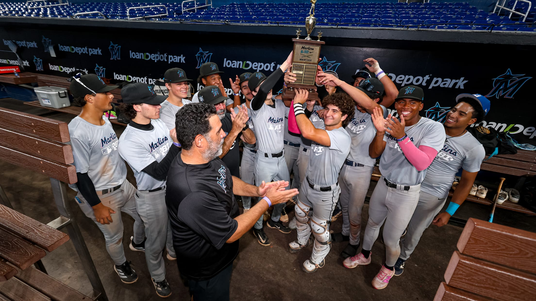 The winning team holds their trophy in the dugout at LoanDepot Park during the Marlins Nike RBI Wood Bat Championship.