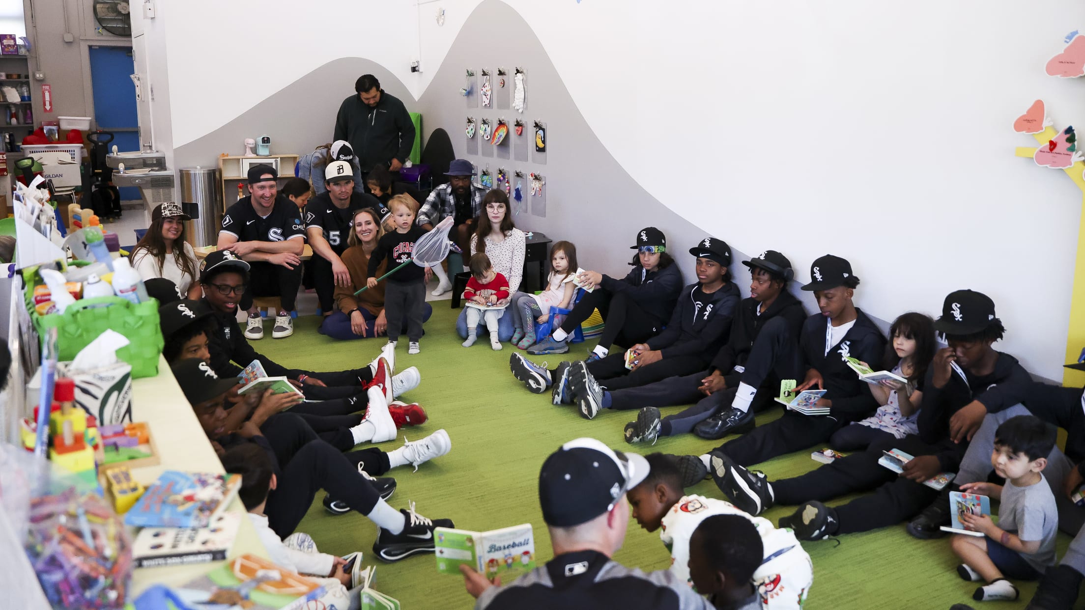 Davis Martin and Erick Fedde listen to youth players and children read from a children's book.