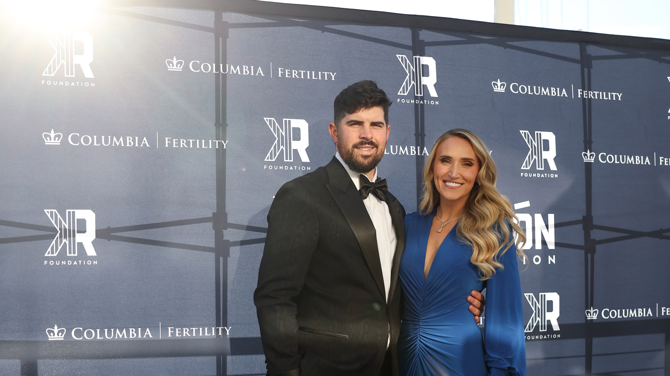 Carlos Rodón and his wife Ashley Rodón pose for a photo in front of Columbia University Fertility Center and The Carlos Rodón Foundation signage.