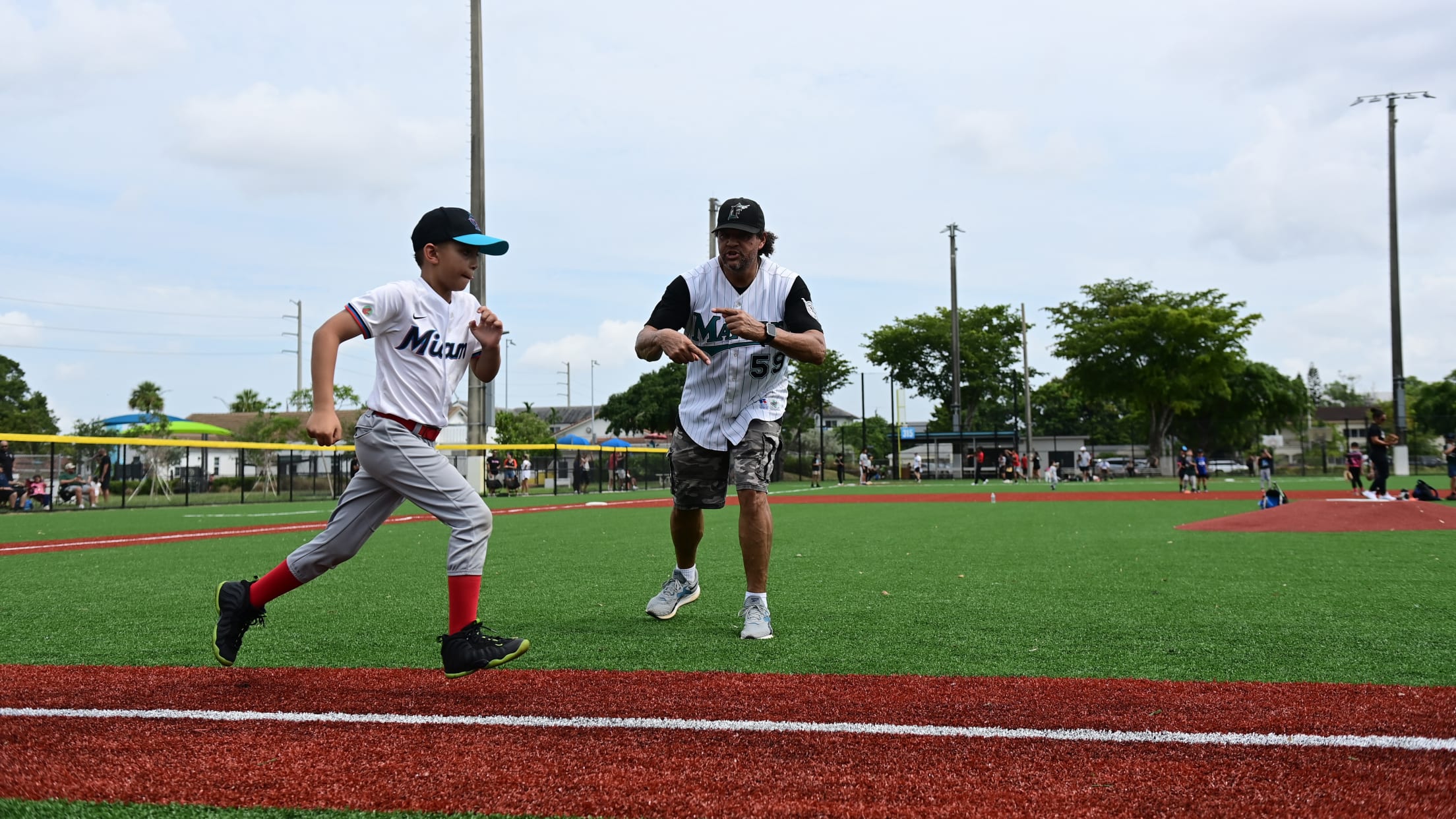 A coach cheers on a young baserunner at the MLBPAA Legends for Youth Clinic.