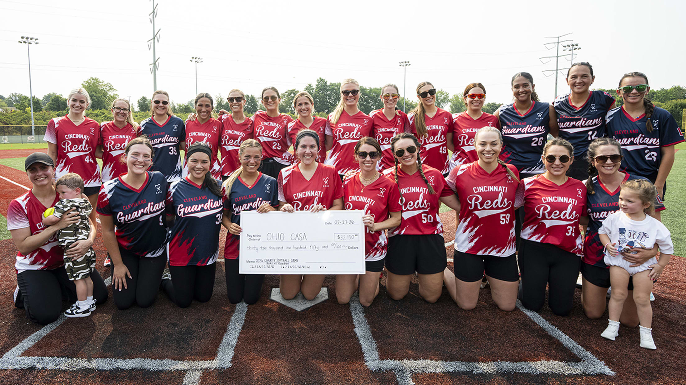 Reds and Guardians wives at home plate with their check for Ohio CASA.