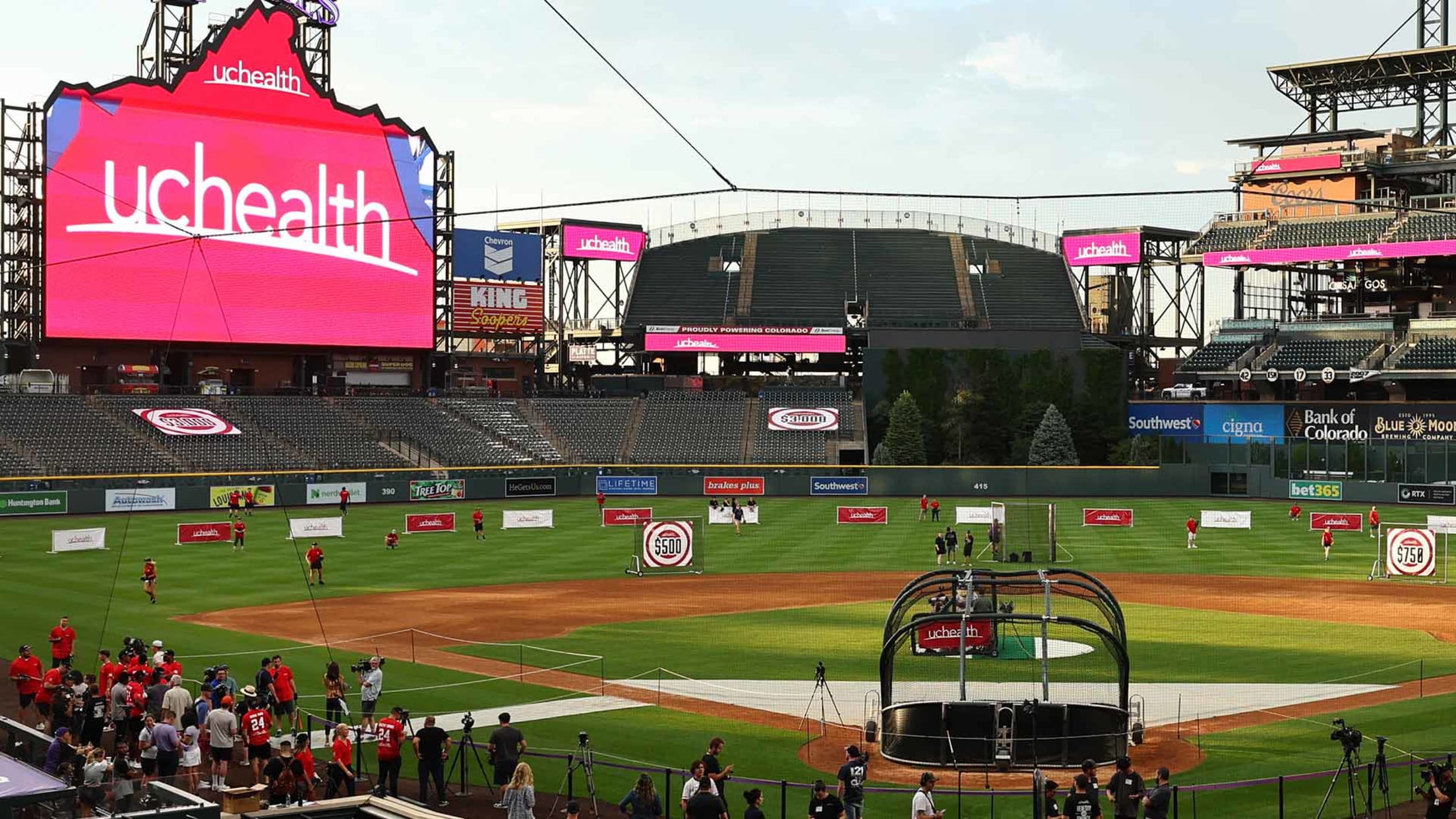 Colorado Rockies Healthy Swings event at Coors Field featuring UCHealth branding, on-field batting practice setup, and participants across the outfield with target stations, highlighting community wellness, youth engagement, and interactive baseball activities in Denver.