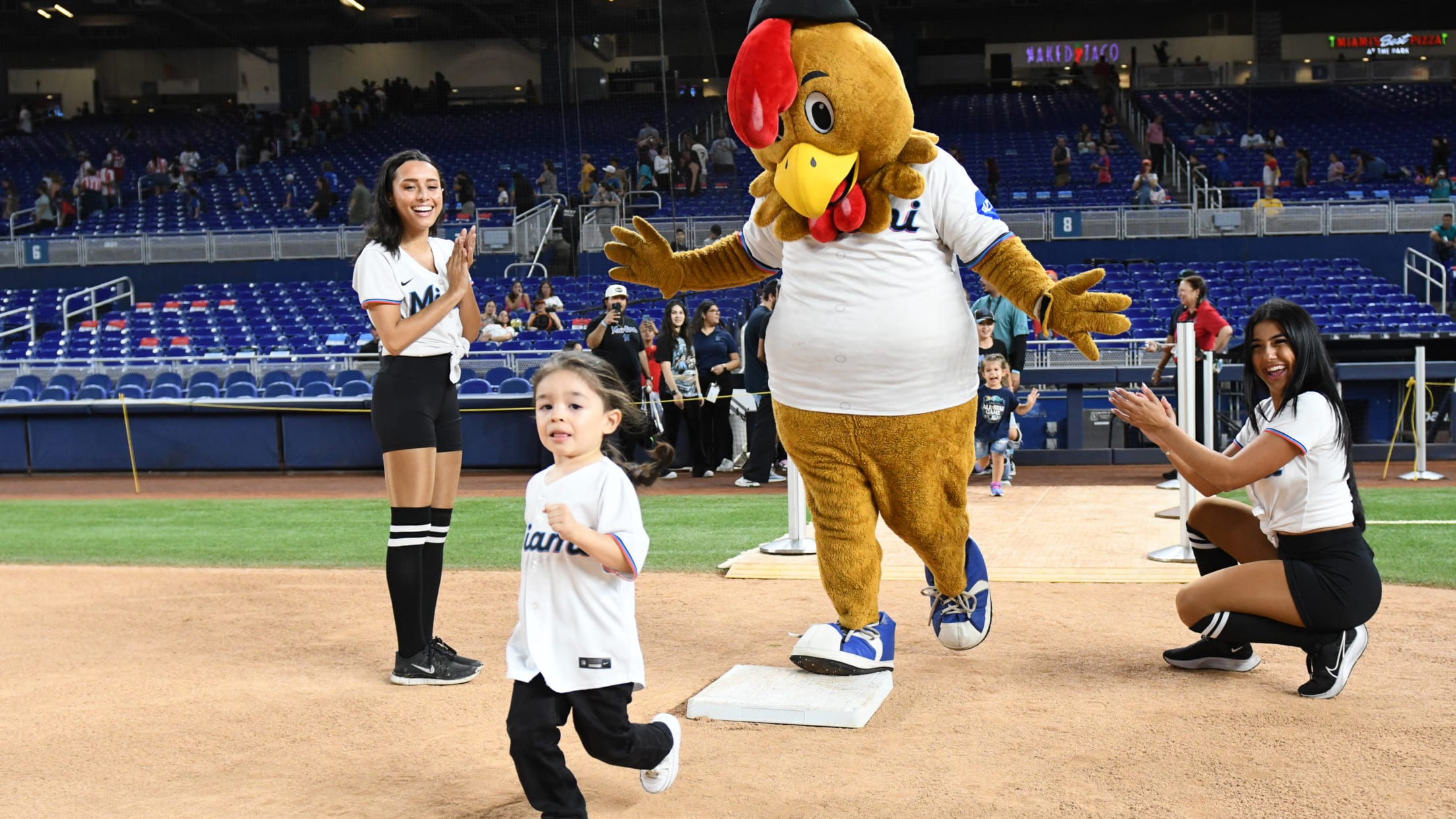 Children running the bases with Marlins mascots
