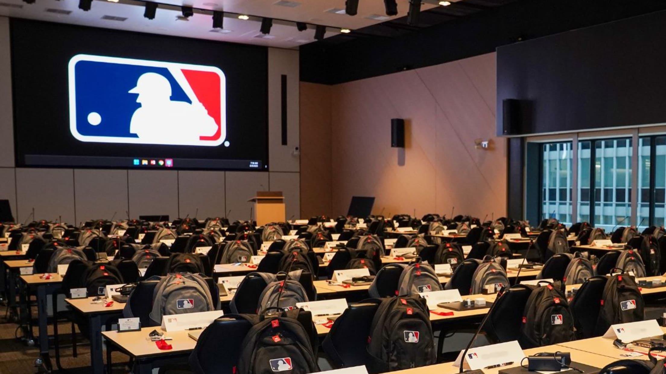 Backpacks on the backs of chairs in the MLB auditorium.