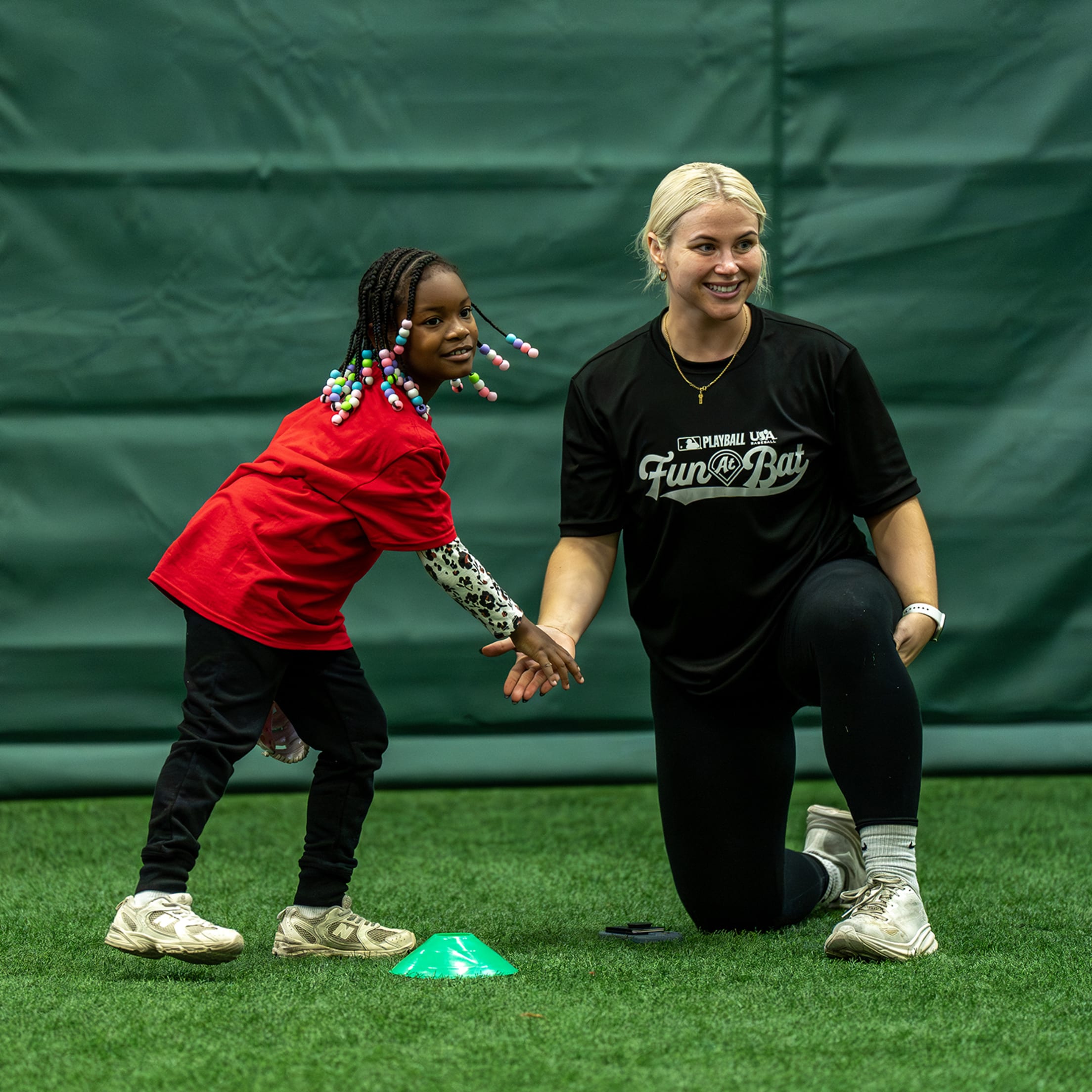 Fun At Bat instructor high-fives young girl during clinic.