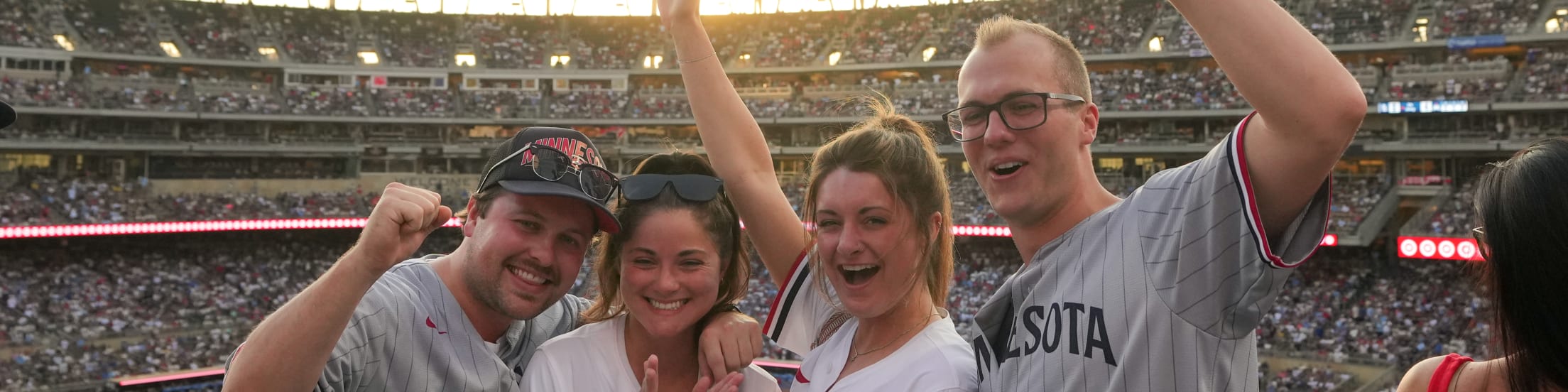 Four friends posing at Target Field while cheering on the Twins