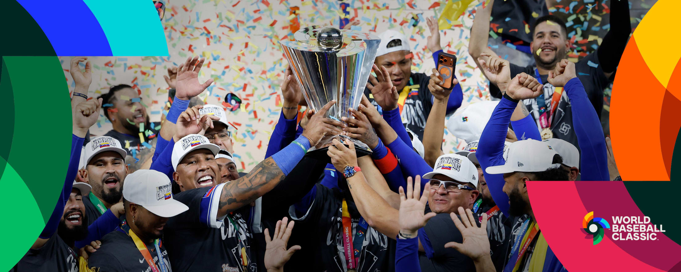 Team Venezuela catcher Salvador Perez and manager Omar López hold the World Baseball Classic trophy in celebration after winning the 2026 tournament.