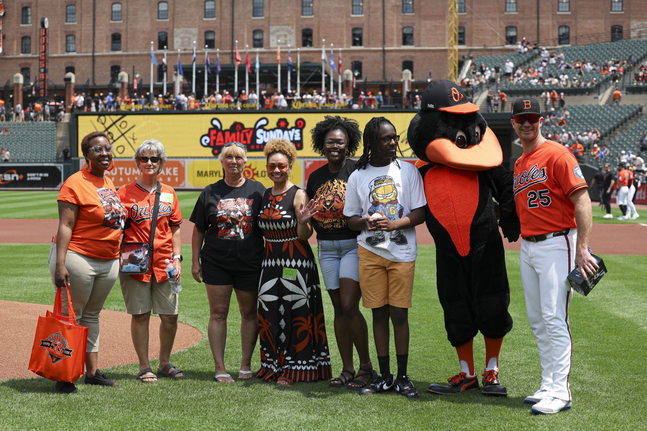 Pete Alonso takes a picture with fans and The Oriole Bird on the field at Camden Yards.