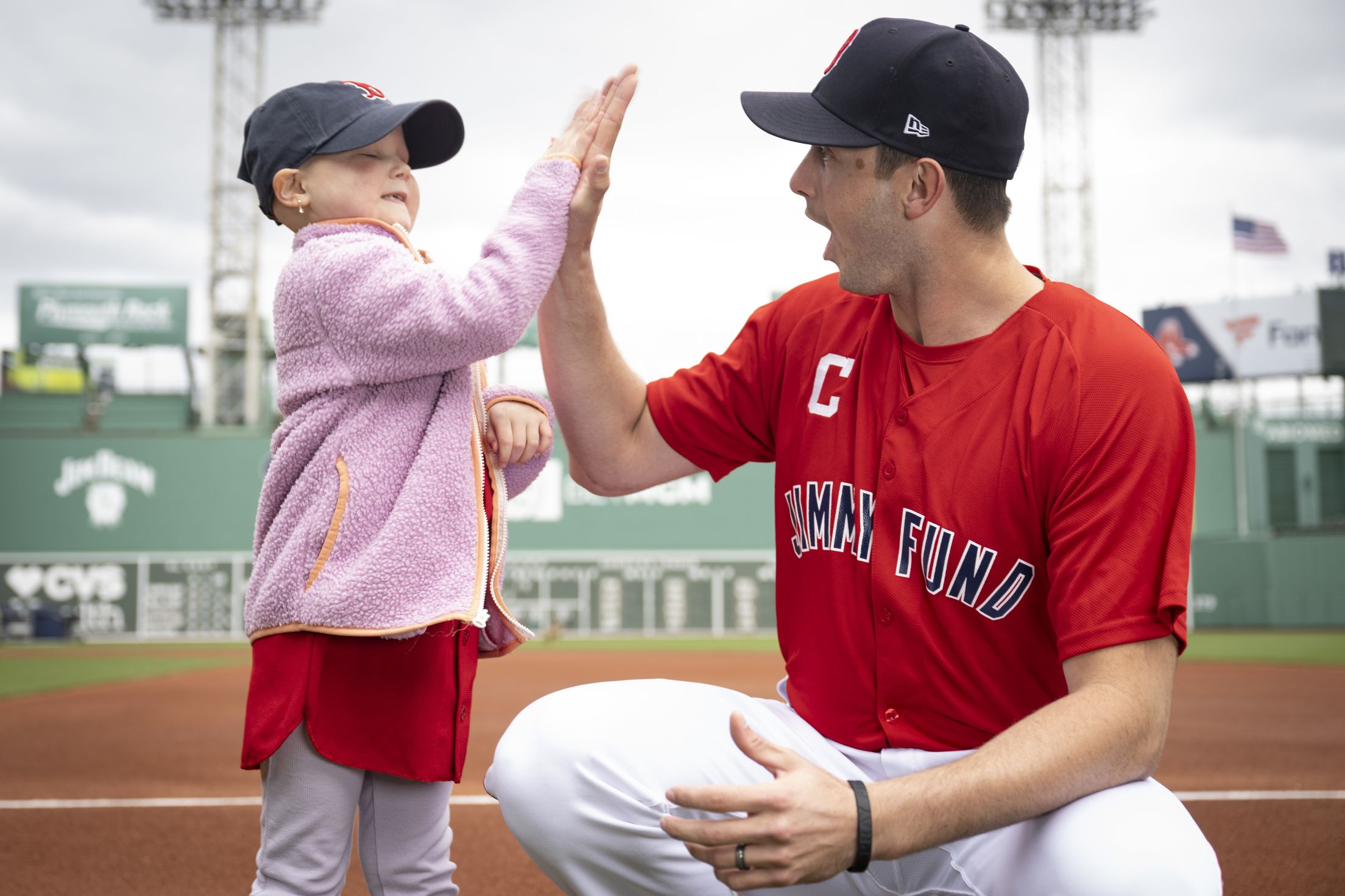 Garrett Whitlock, a Jimmy Fund Captain, high-fives a Boston Red Sox fan.