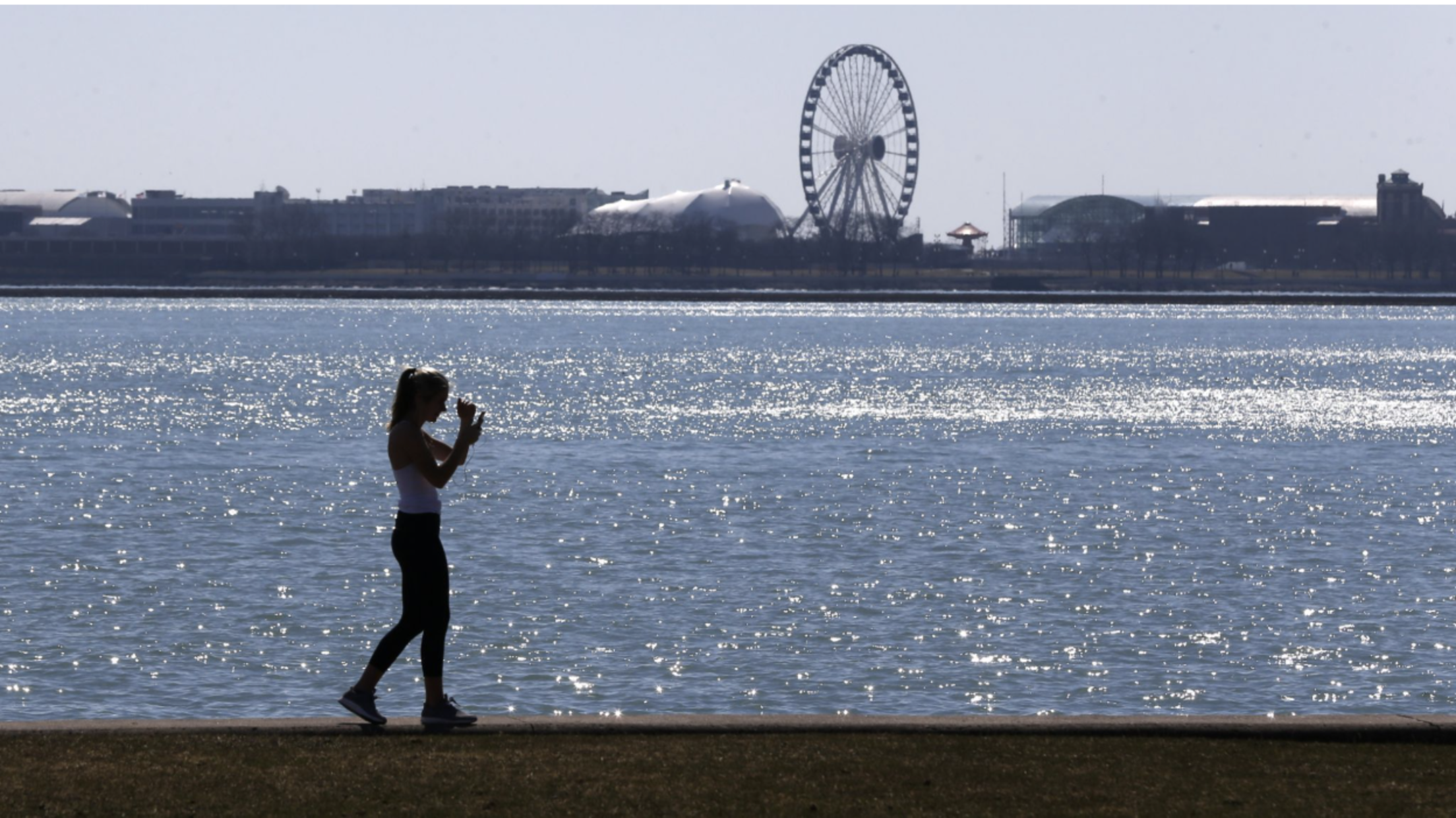 jogger-running-along-lake-michigan-shoreline-with-navy-pier-ferris-wheel