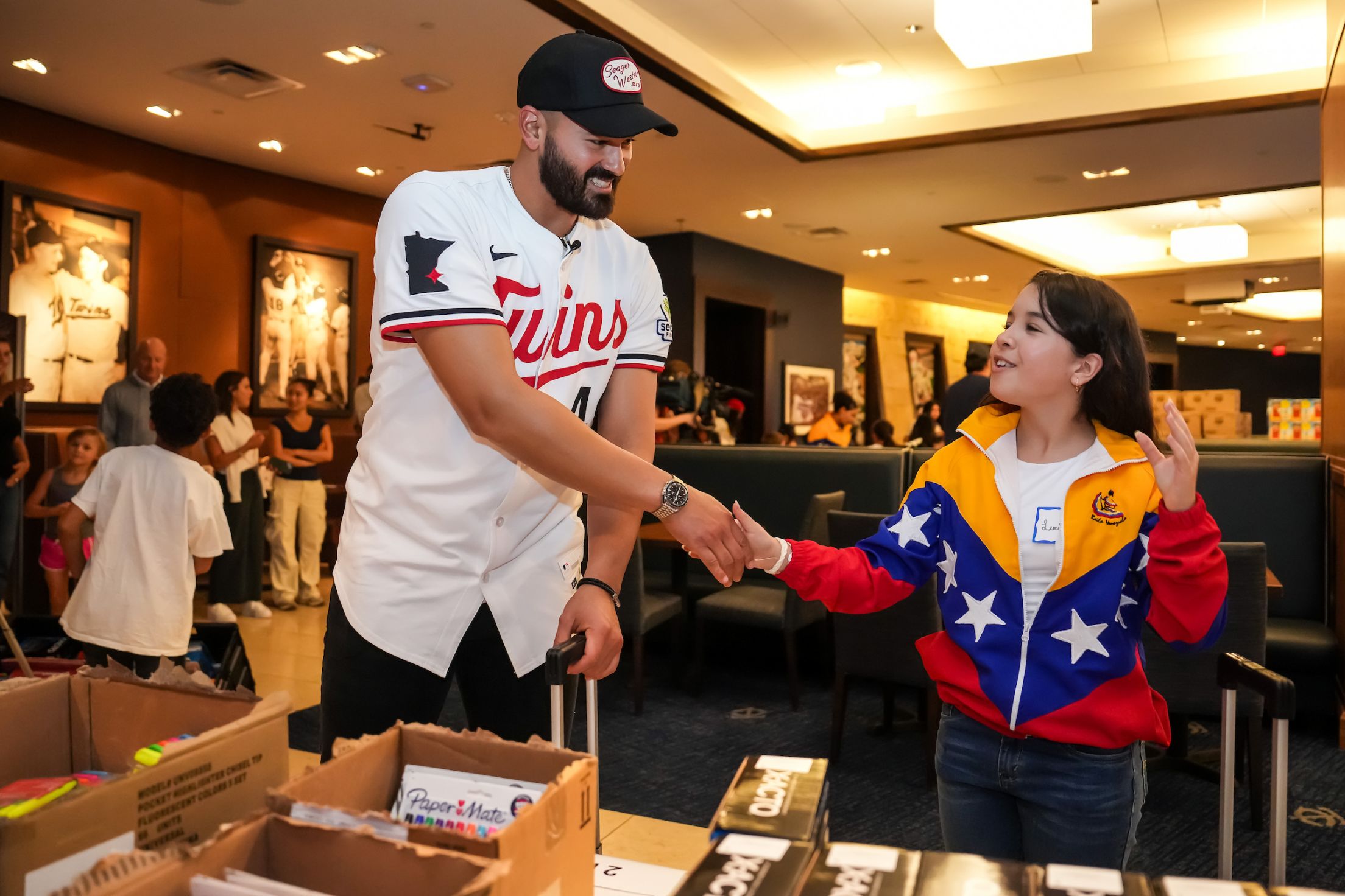 Pablo López shakes hands with a fan as they attend a school supply event.