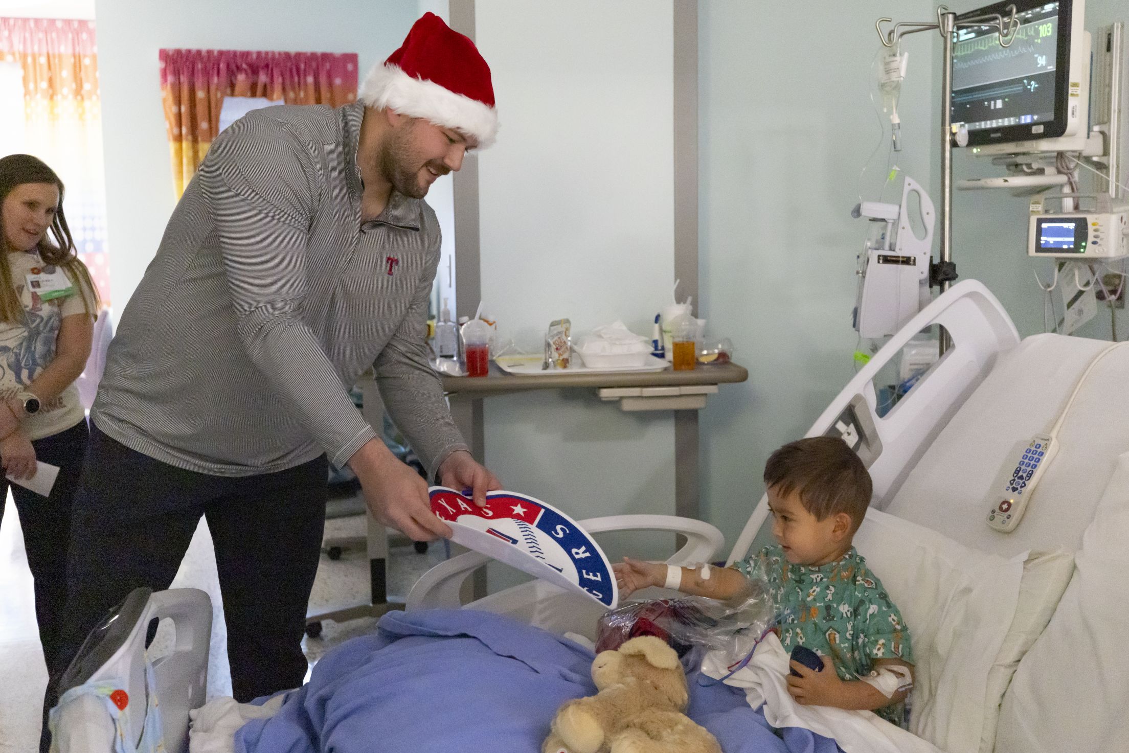 Jake Burger hands a young fan a Texas Rangers poster during a hospital visit.