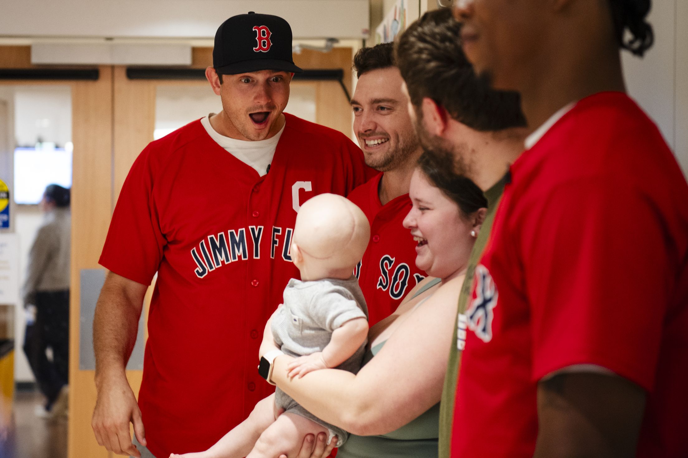 Garrett Whitlock plays with a baby as they pose for a photo.