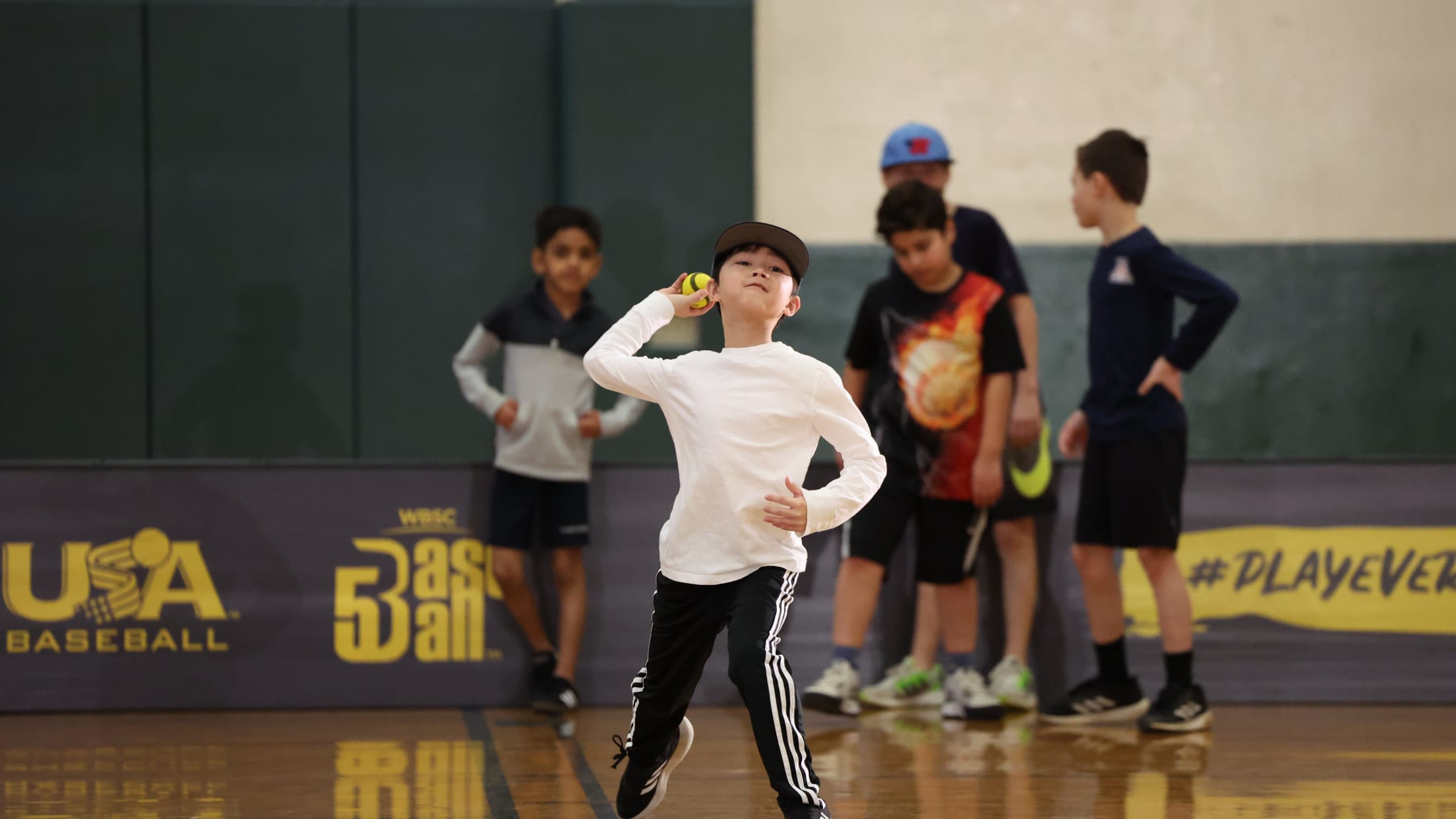 Child throws a ball in a gym as part of USA Baseball's Baseball5