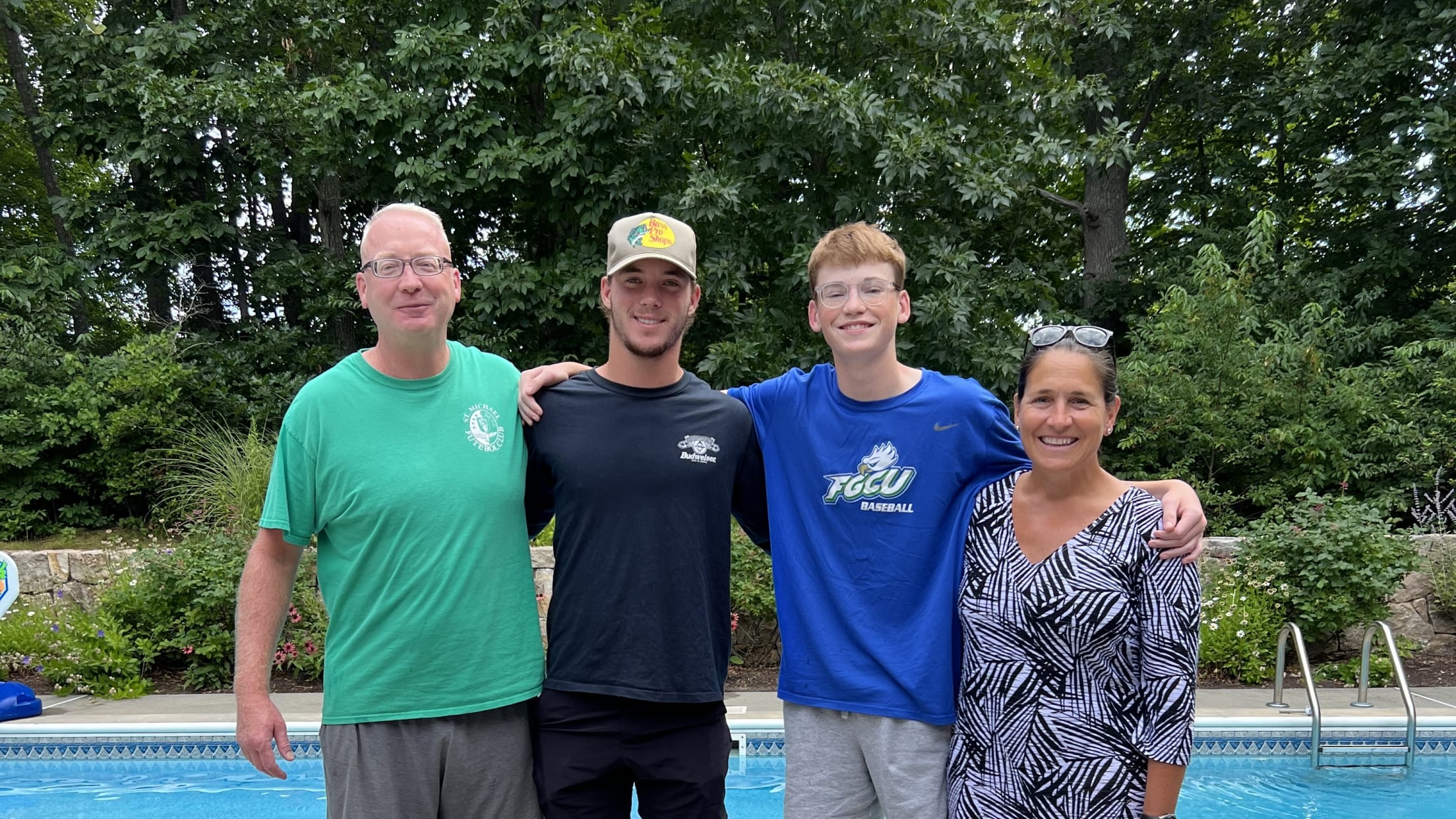 Gatemen player poses with his host family at their home in front of their pool with their dog in front.