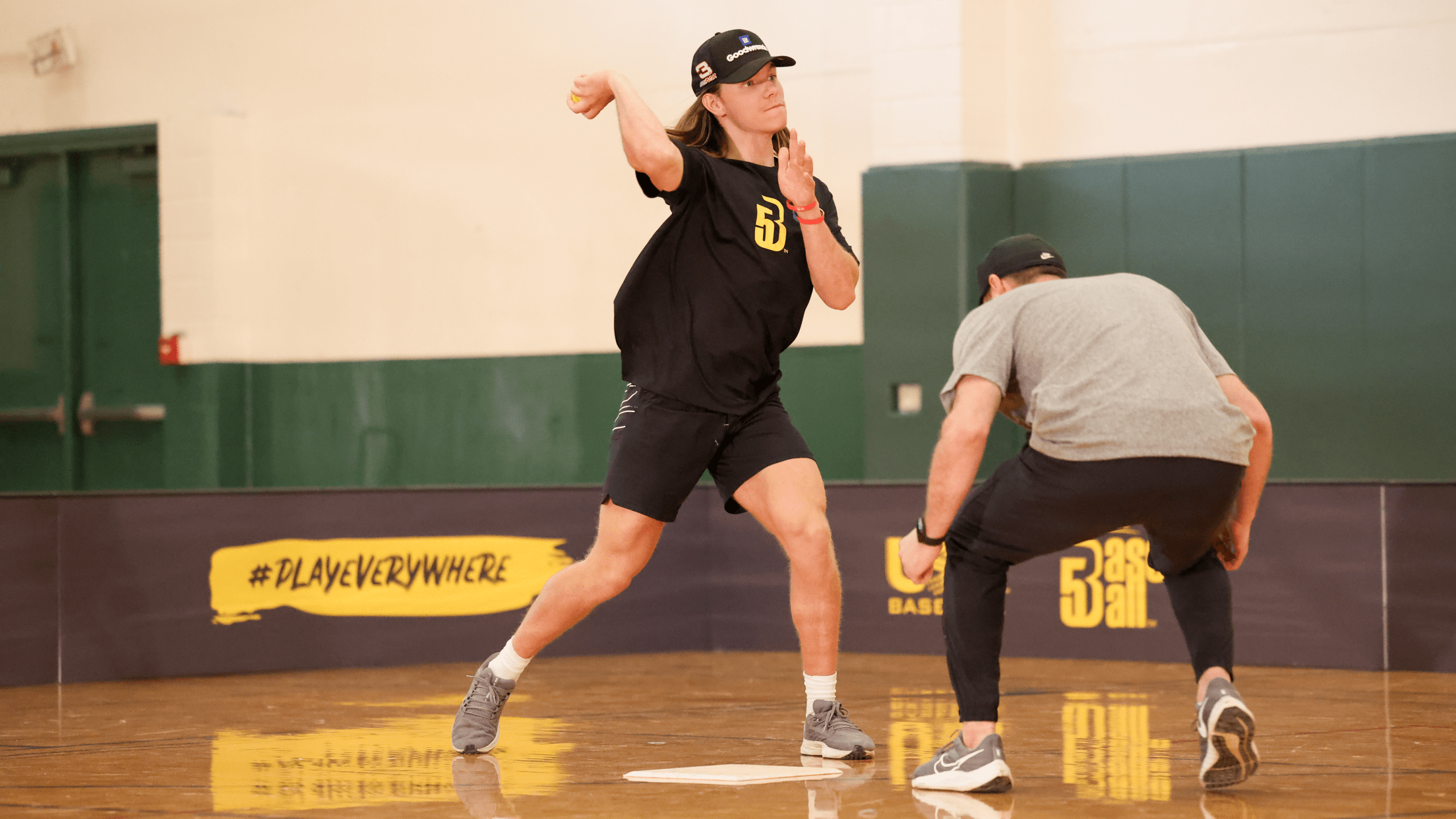 Person playing Baseball5 in a gymnasium.