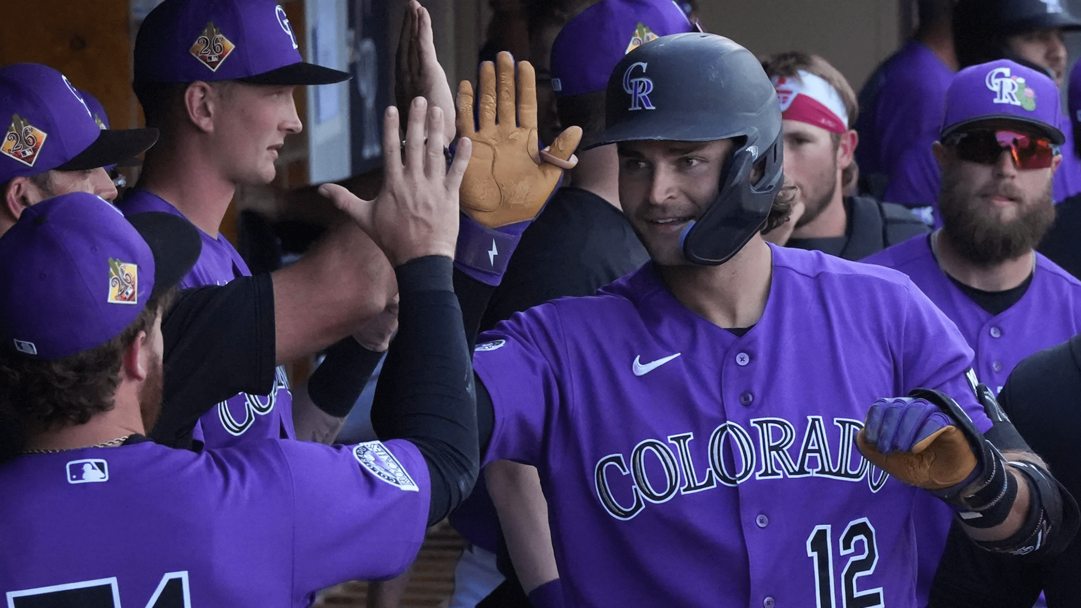 Kyle Karros receives high fives in the Rockies dugout after scoring a run during a 2026 Spring Training game.