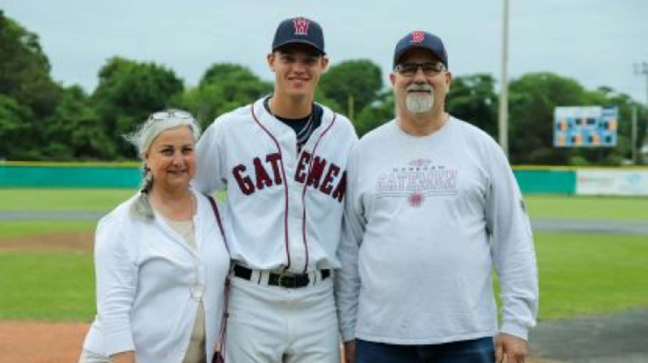 Wareham Gateman player stands near home plate with his host family.