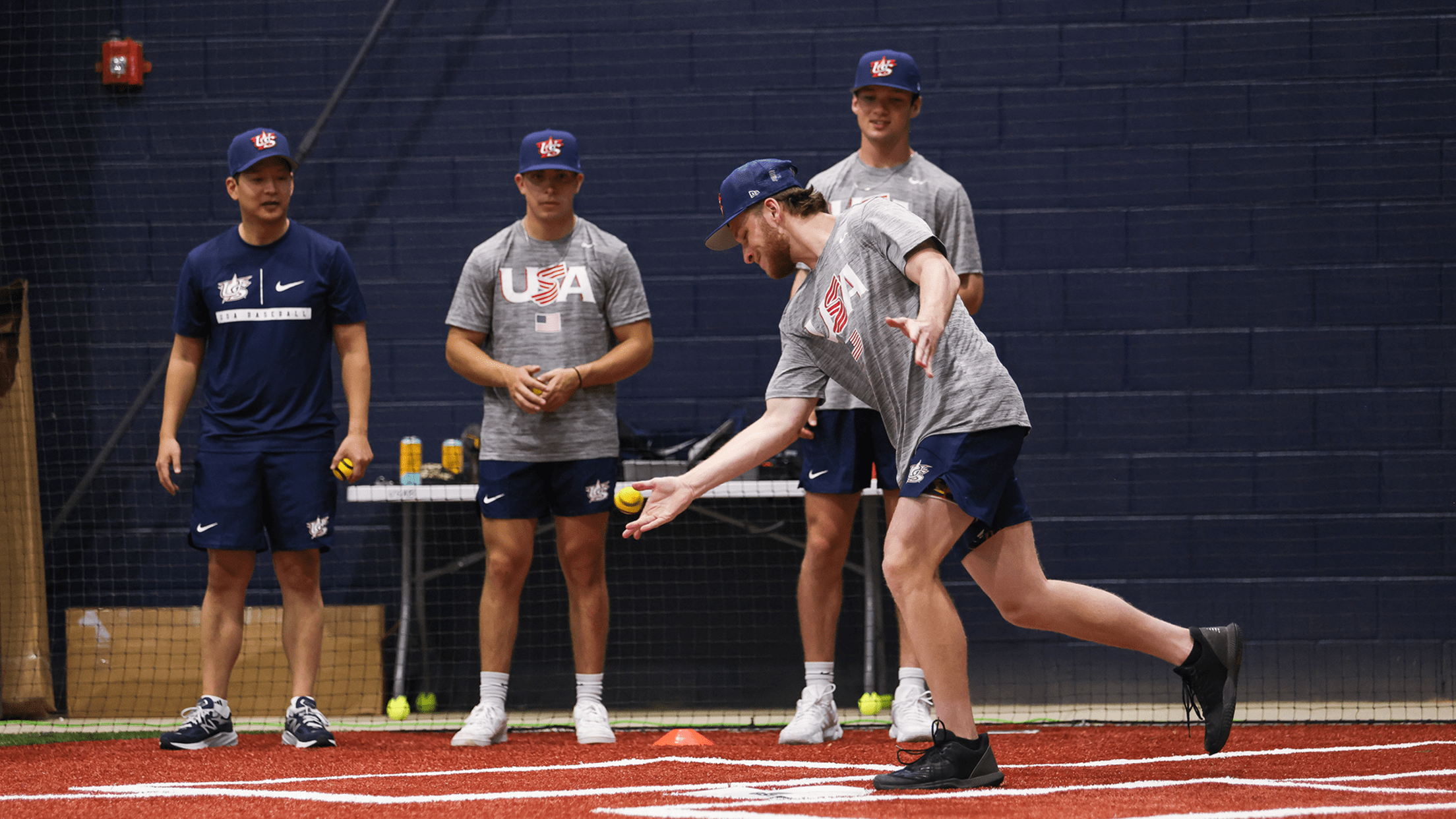 one player hitting a baseball5 ball while other players behind him in team usa gear watch