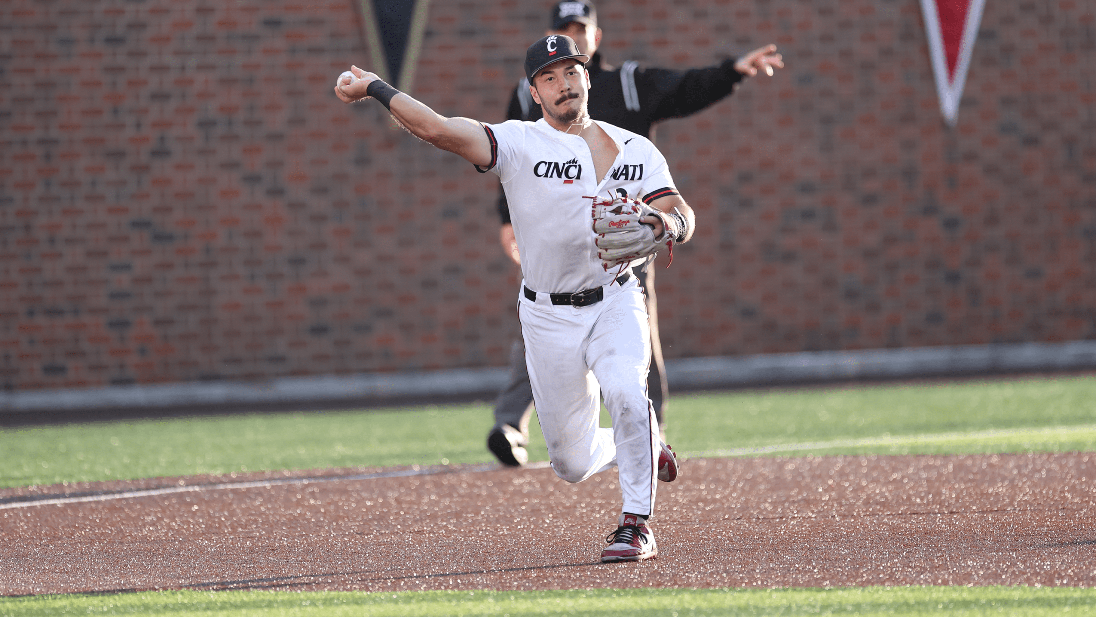 Cincinnati infielder Kerrington Cross throws a ball to first base.