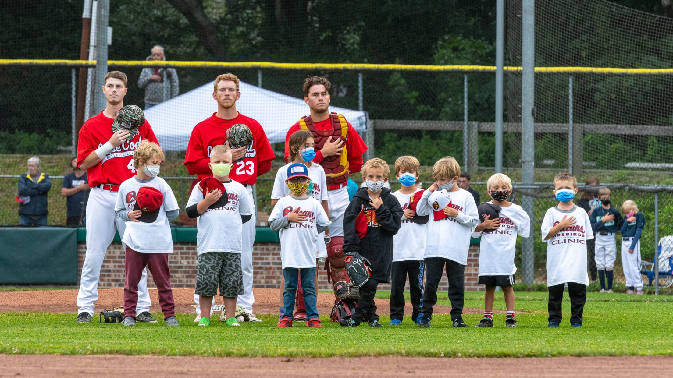 Three Firebirds players stand with nine children during the national anthem.