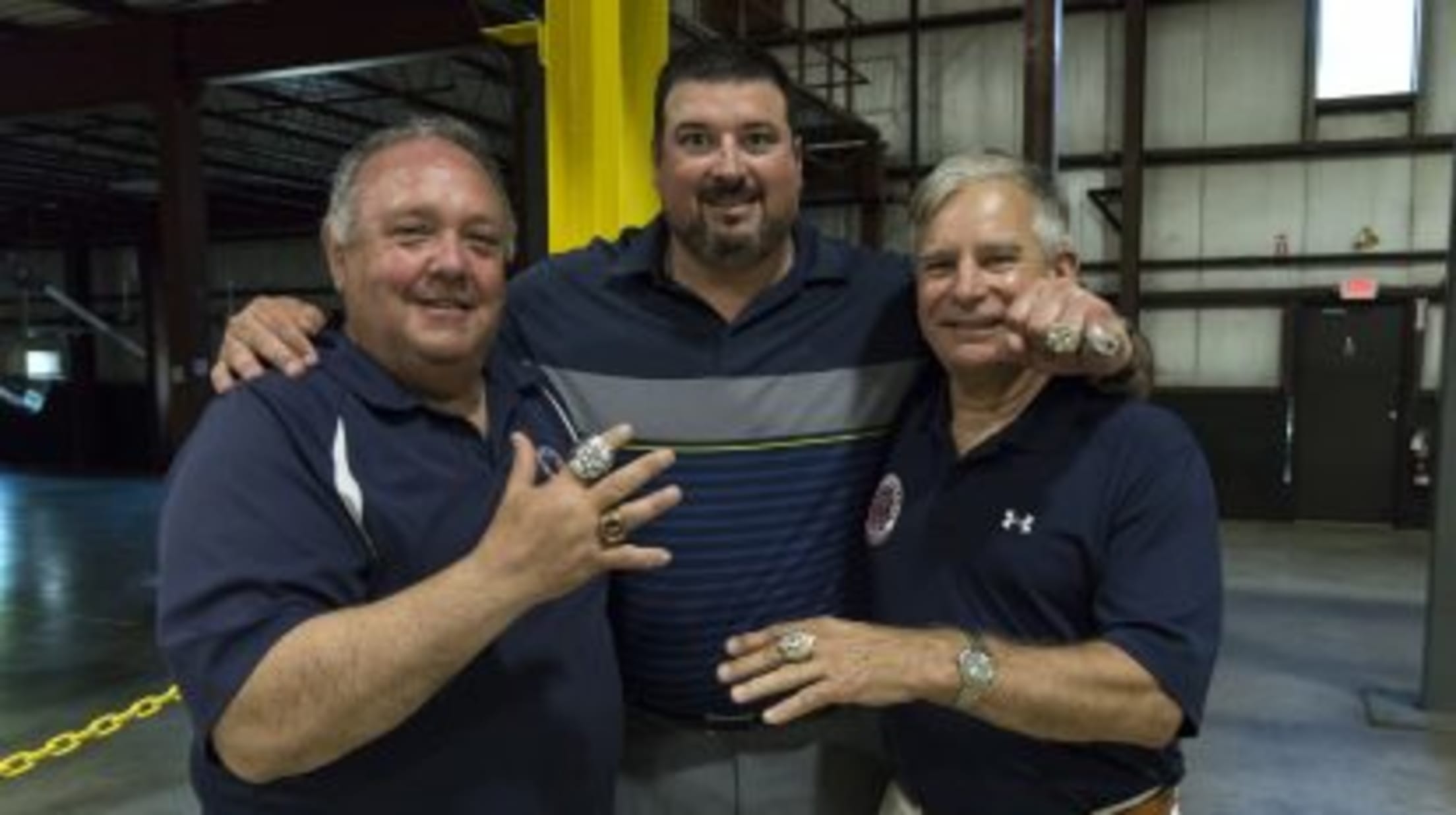 Three men pose with their championship rings.