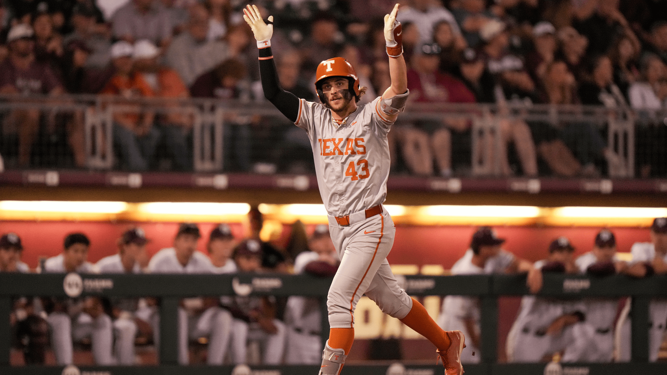 Texas outfielder Aiden Robbins raises his arms in celebration as he approaches home plate after a home run.