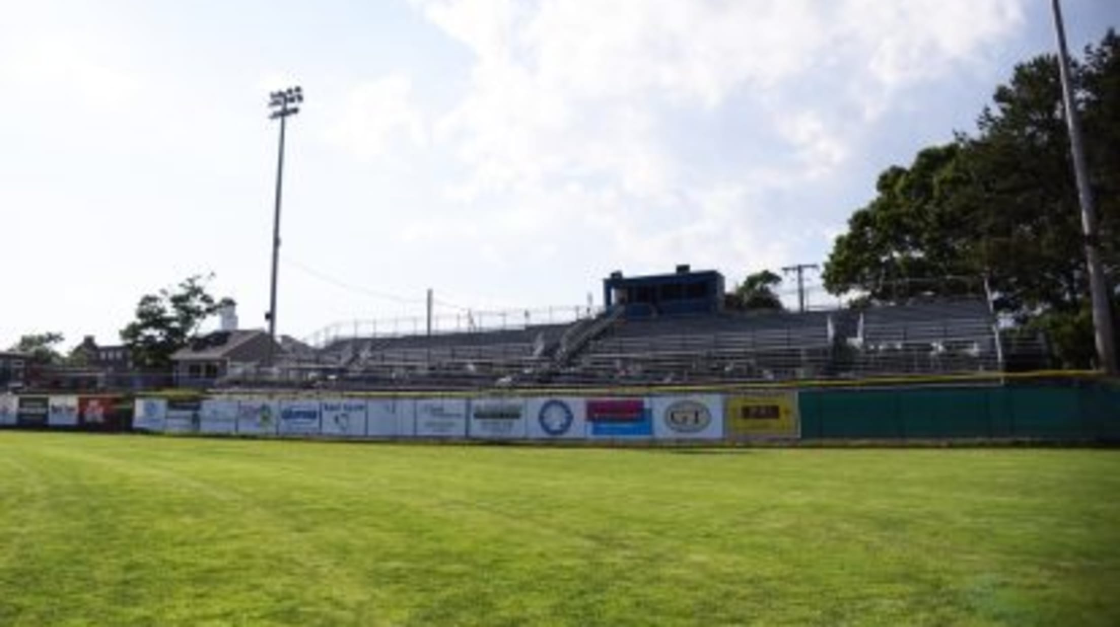Spillane Field outfield wall and seating with advertisements strewn across the outfield wall.