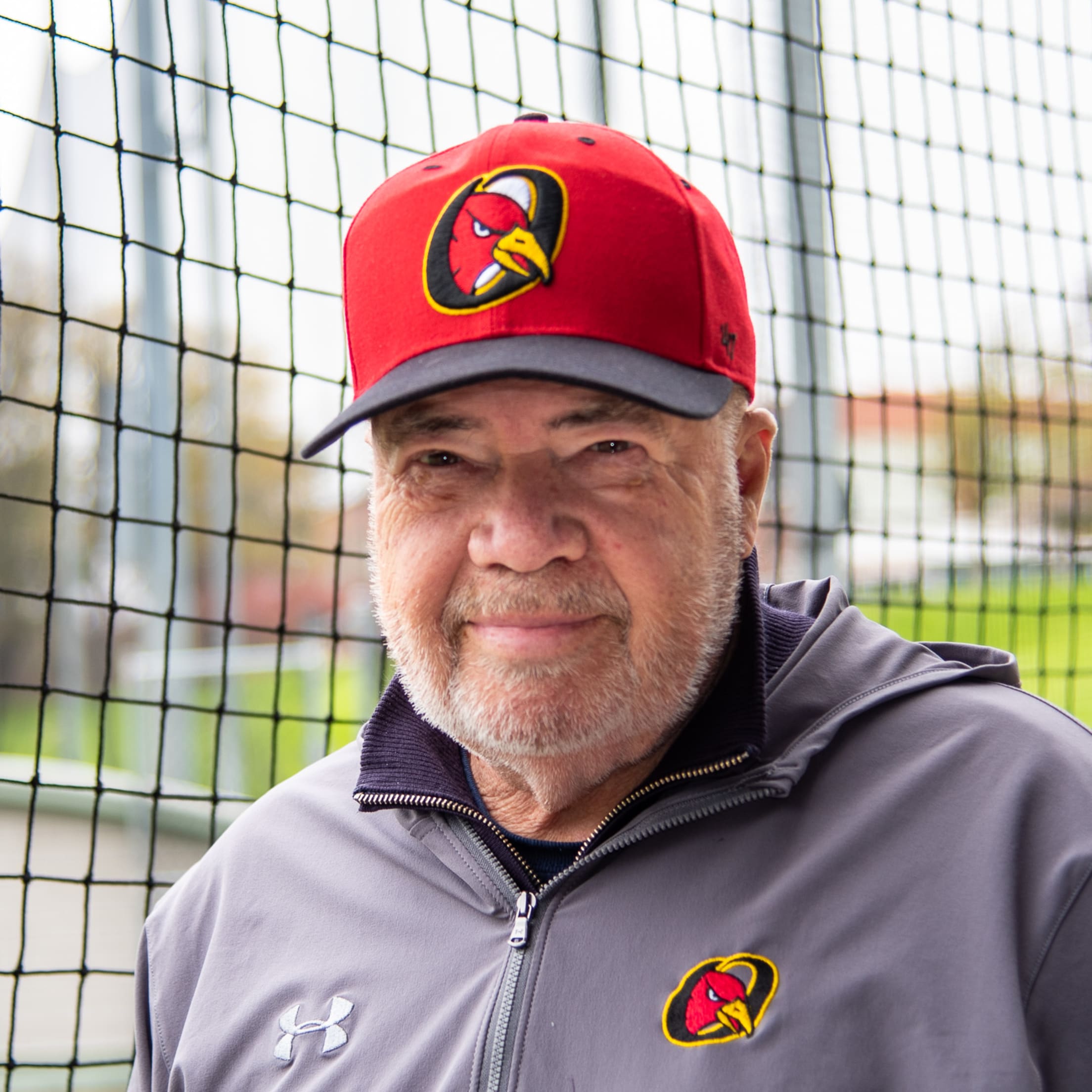 Orleans Firebirds President Bob O'Donnell stands in the dugout for a portrait with an Orleans Firebirds hat and an Orleans Firebirds quarter-zip.