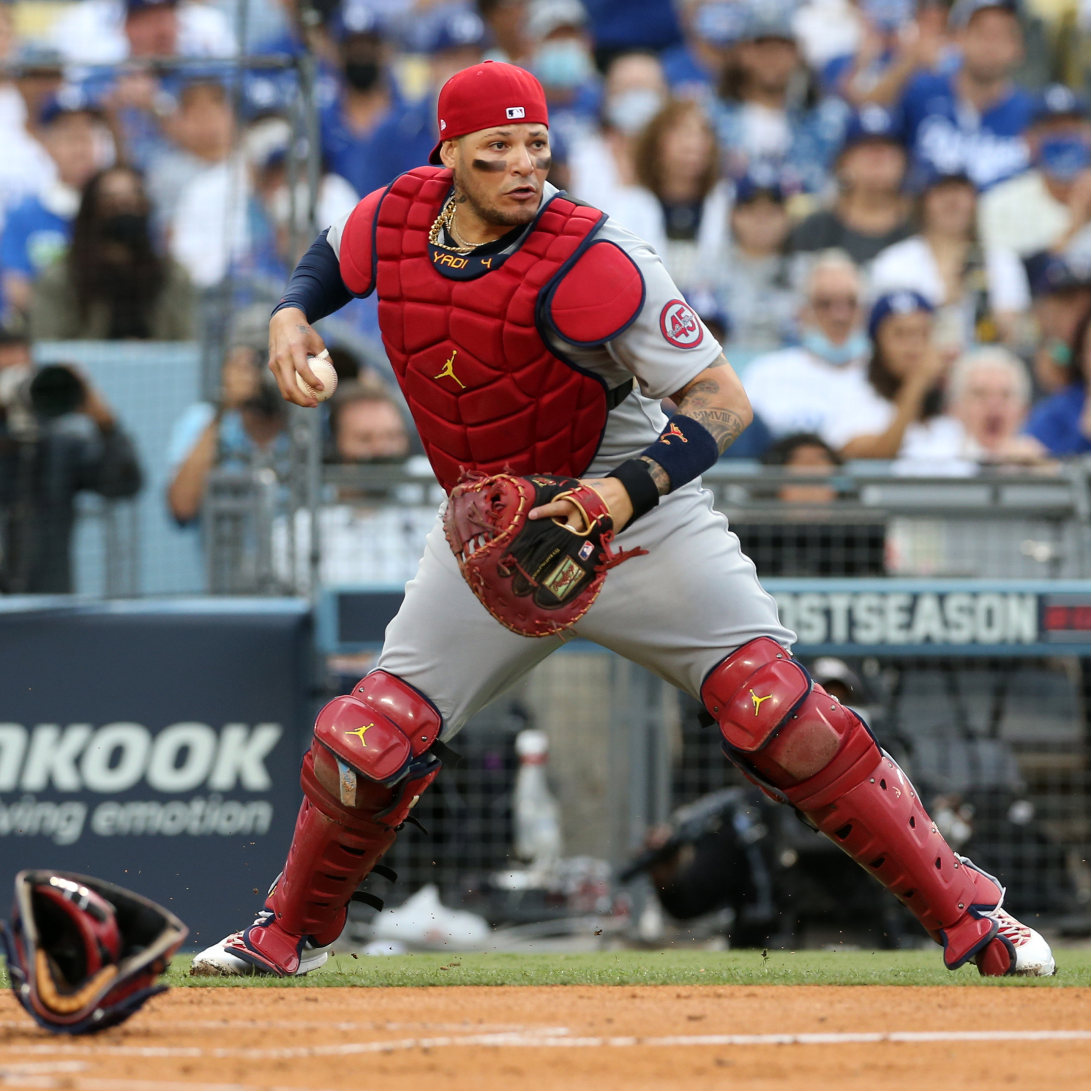 St. Louis Cardinals catcher Yadier Molina holds the ball with his mask off, standing up around home plate, geared to throw as he peers towards first base.