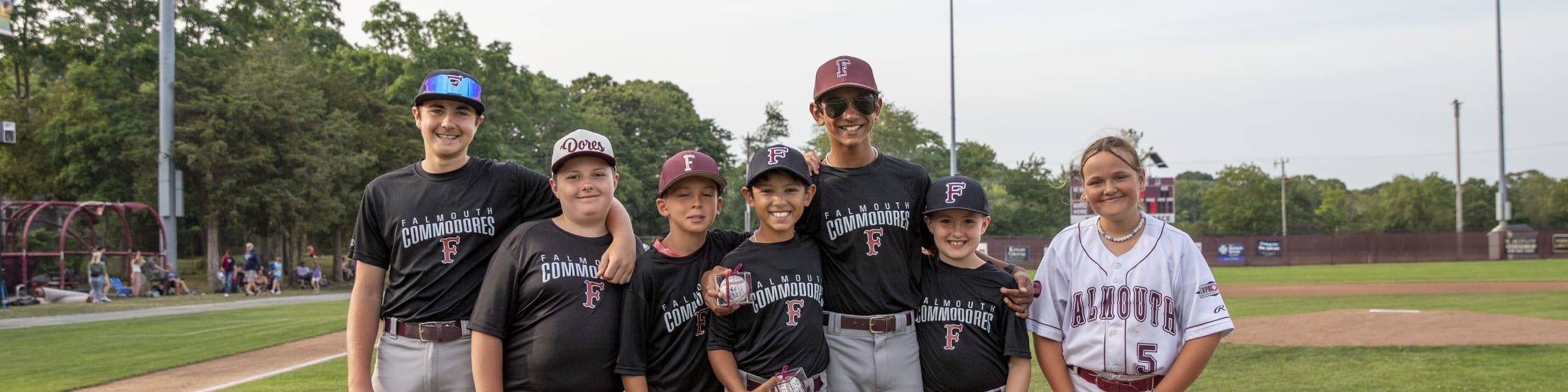 Seven Falmouth Commodores Bat Kids pose for a photo on the first base live at Guv Fuller Field.